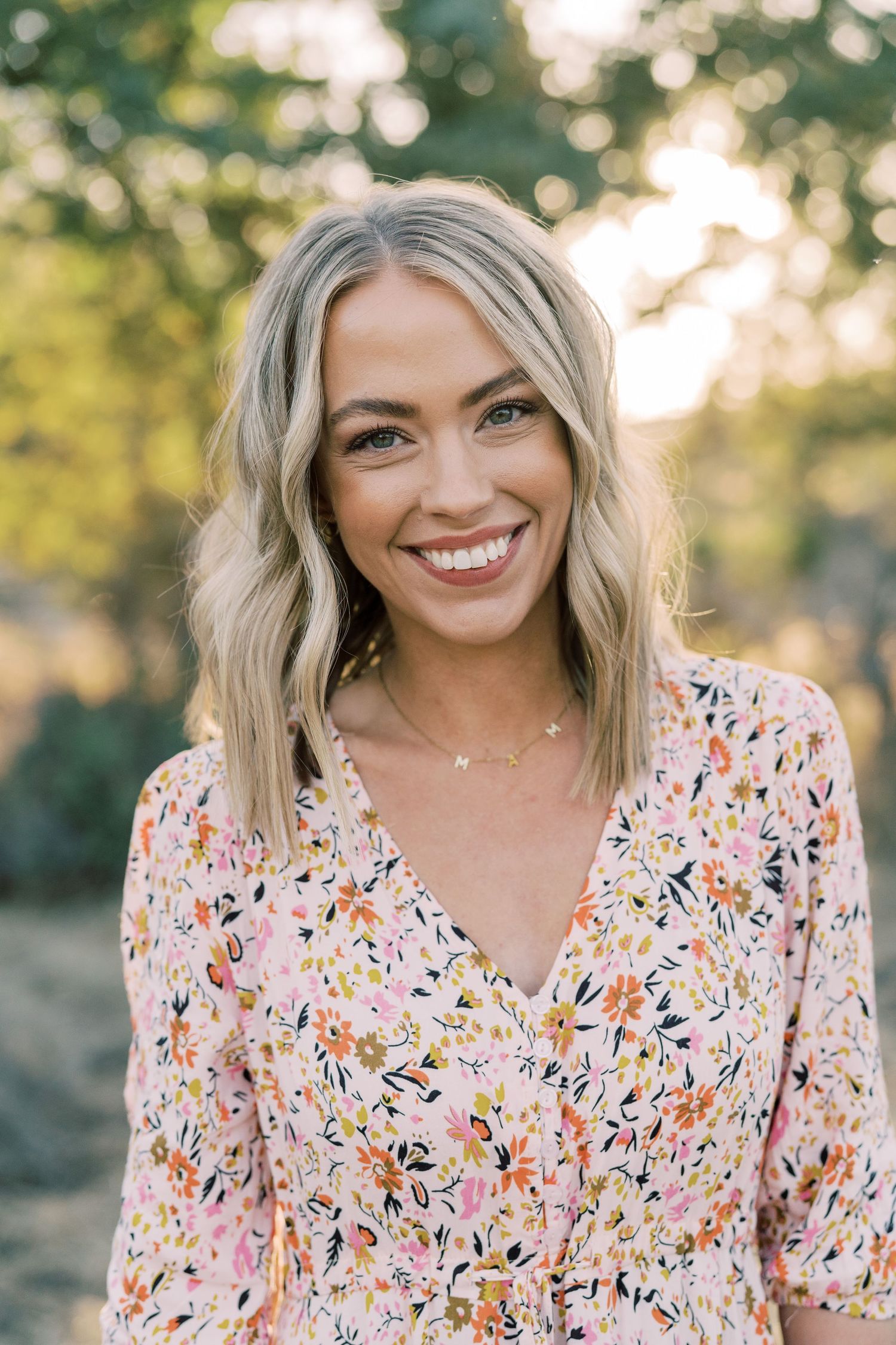 A floral print dress in soft pink and orange tones glows in warm natural lighting.