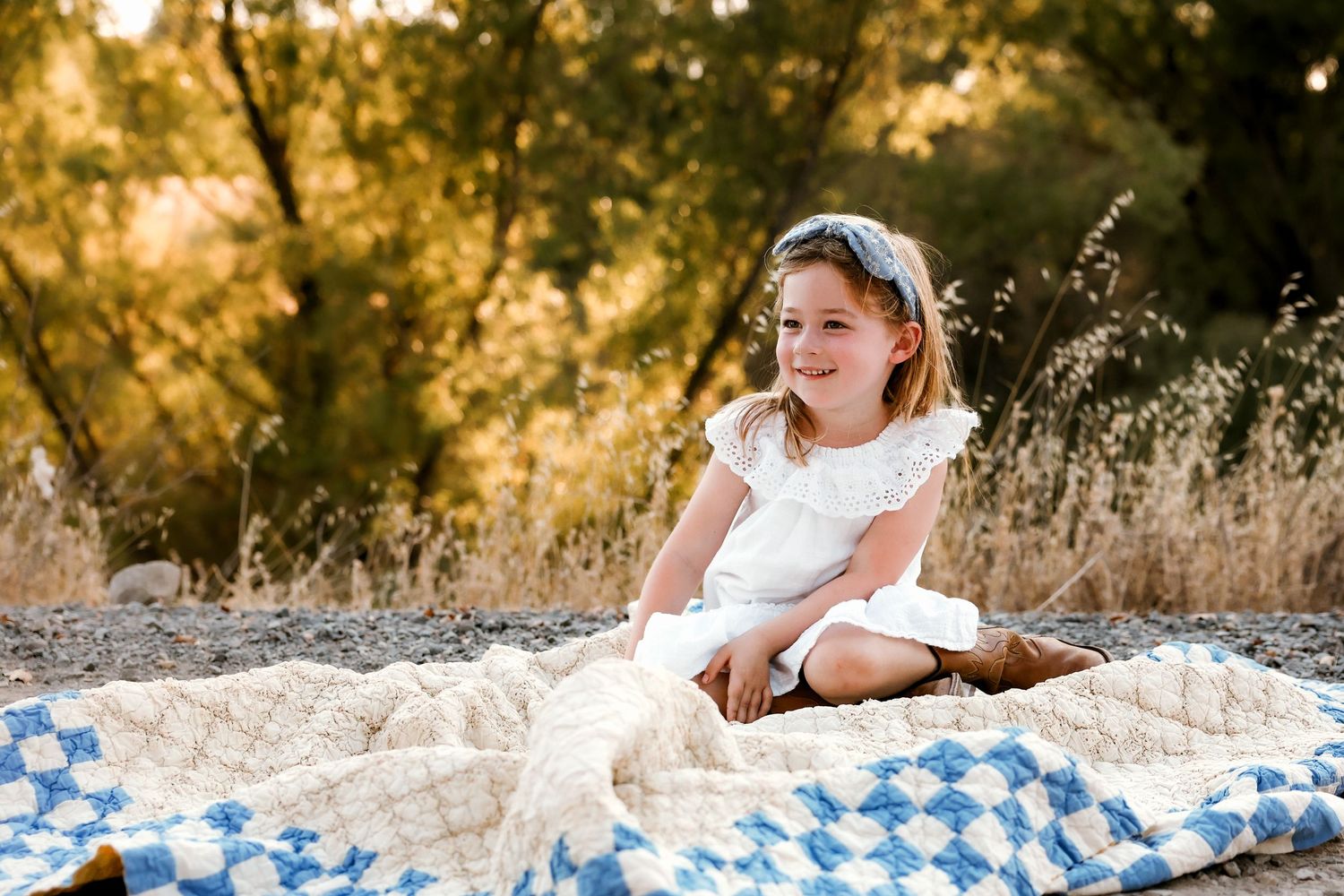 A blue and white checkered blanket laid out on rocky ground at sunset.