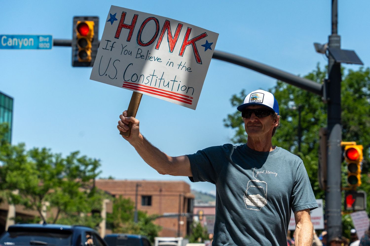 Group of protesters holding signs at street intersection with traffic light.