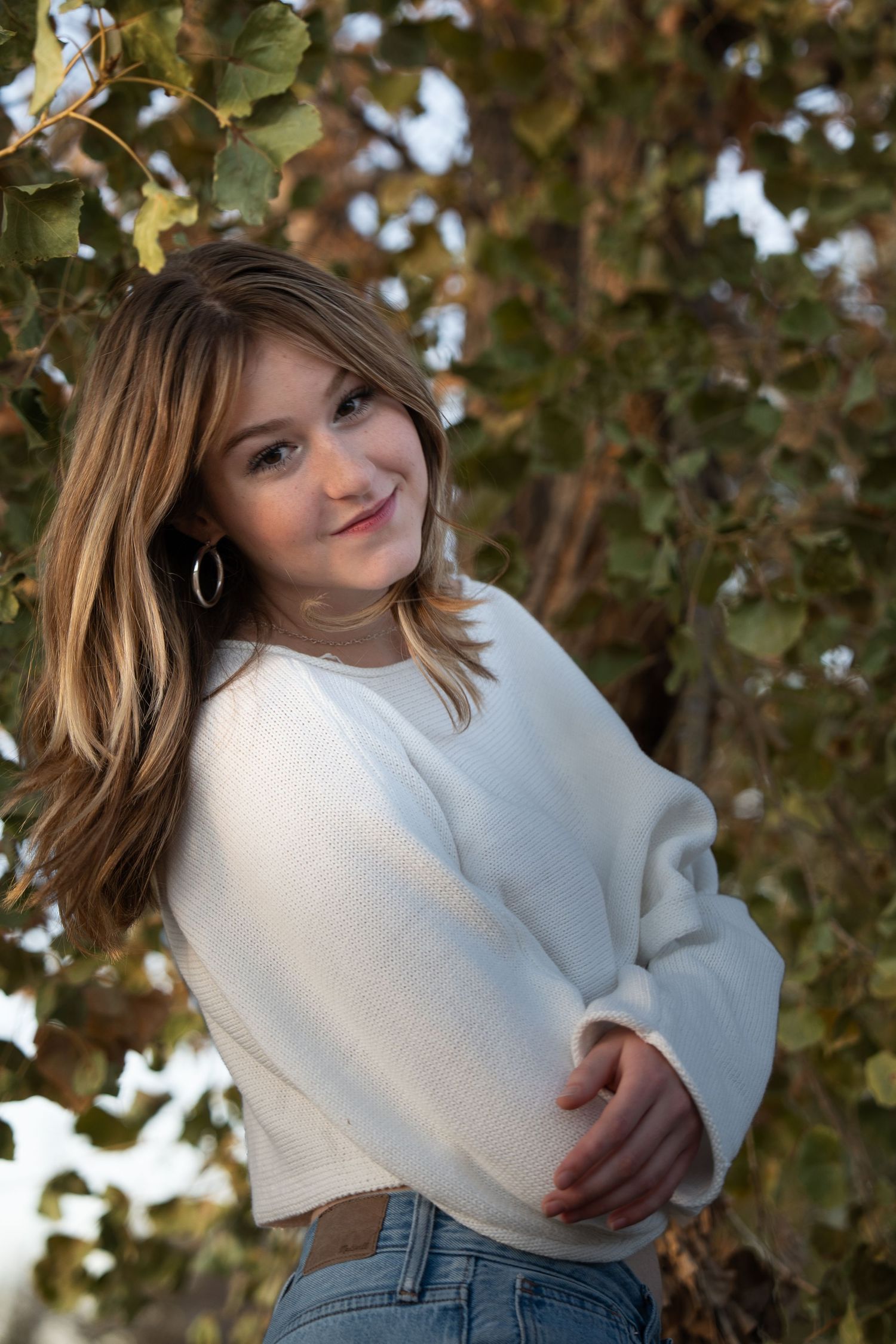 Portrait series showing person in white sweater posing near autumn foliage.