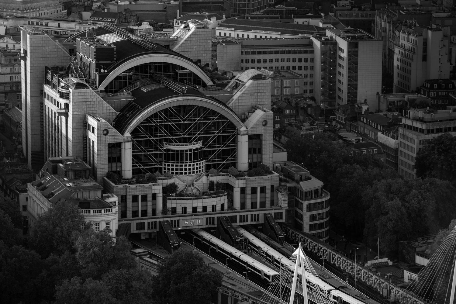 Aerial view of a grand railway station with curved arched roof architecture in black and white.