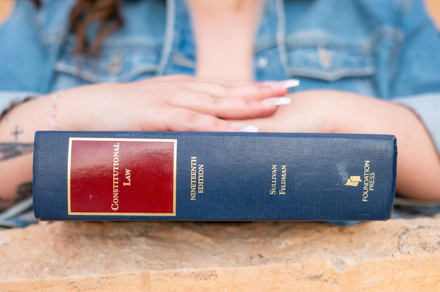 A woman's hands clasped on top of a constitutional law textbook in Laramie, Wyoming.