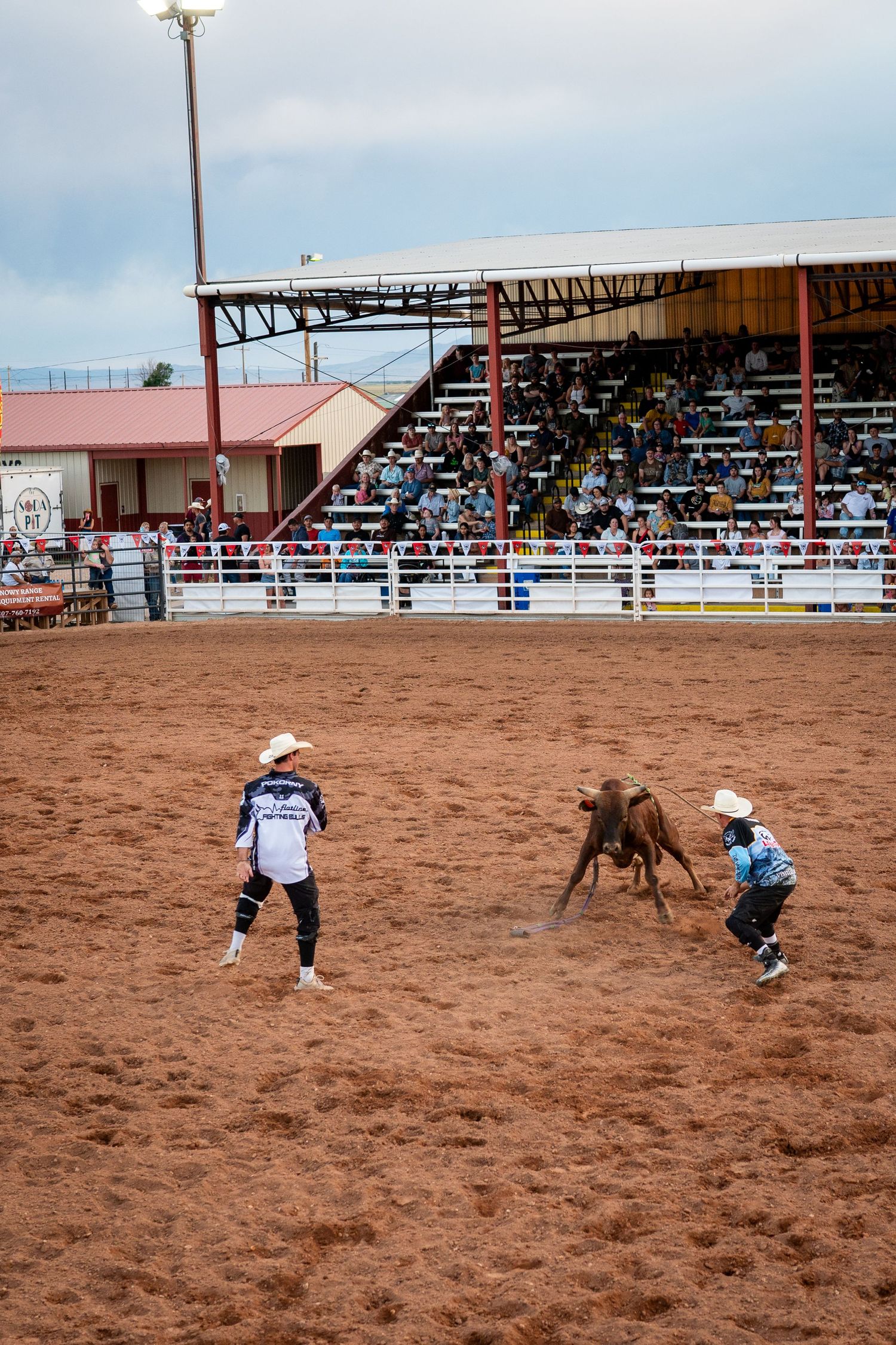 Two bull fighters at a rodeo jump in front of a red bull at he Albany County Fairgrounds in Laramie, Wyoming.