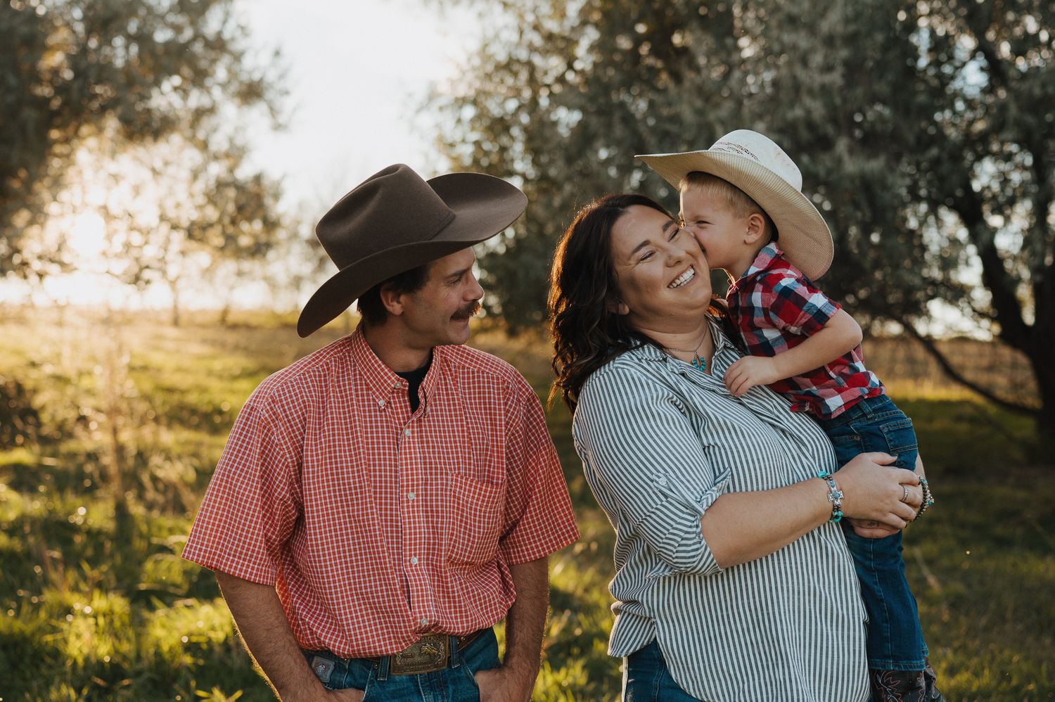 A loving family shares joyful moments together outdoors during golden hour in a sun-dappled grove.