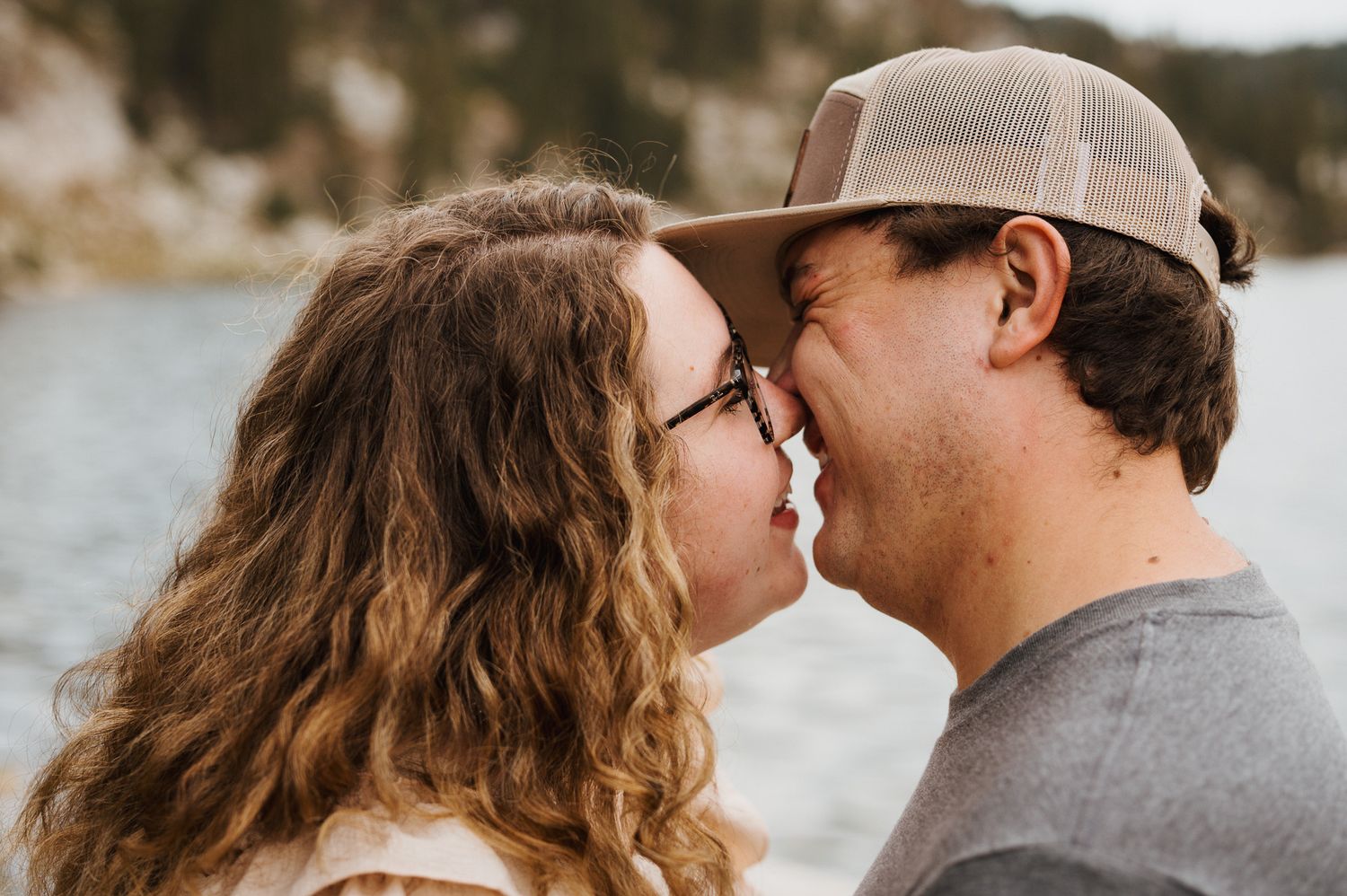 A romantic couple embraces and kisses on during sunset with Mirror Lake in the background.