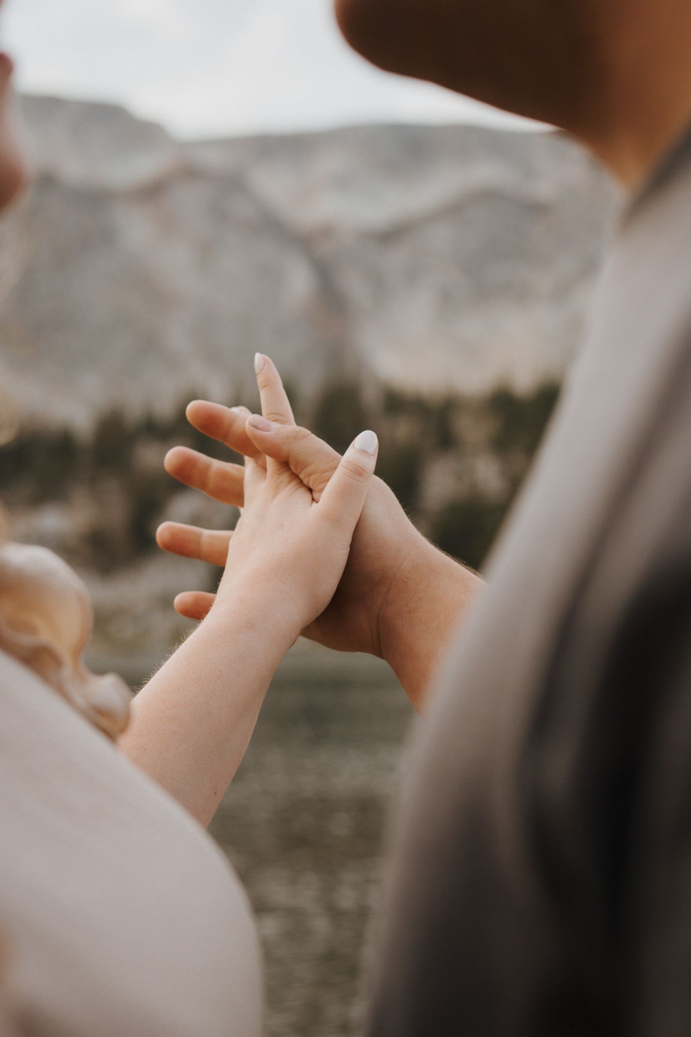 Hands reaching out in a sequence of motion against a blurred mountain landscape background.