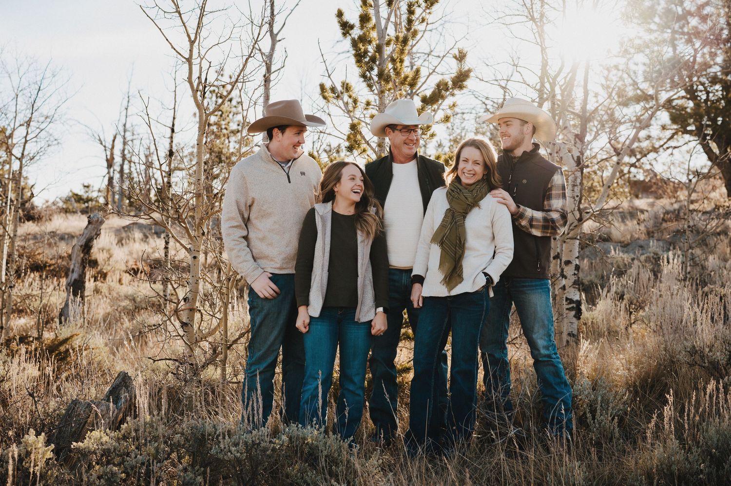 A family in coordinated blue and white outfits poses together outdoors during a fall photoshoot.