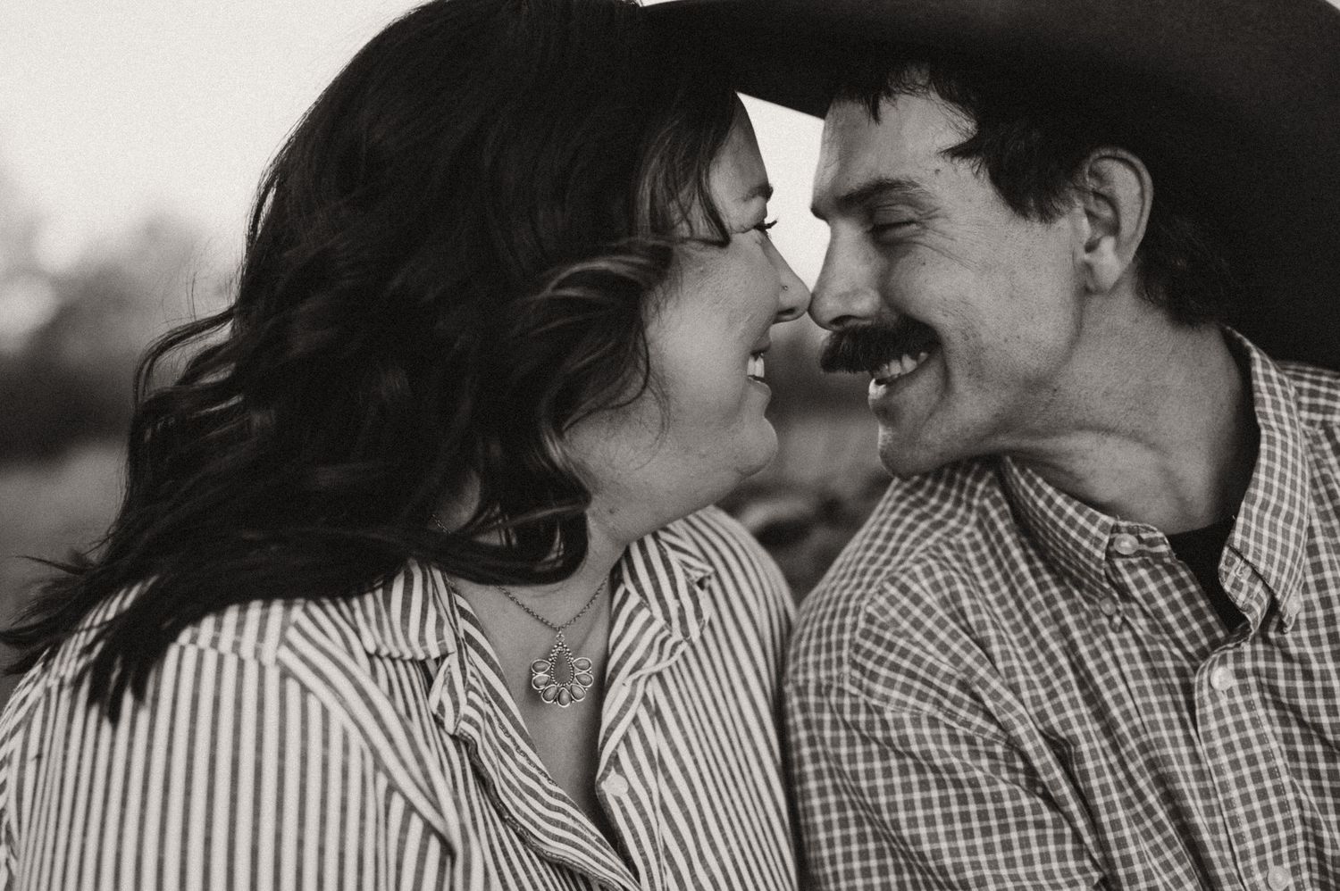 A husband and wife smiling at each other with their faces close together.