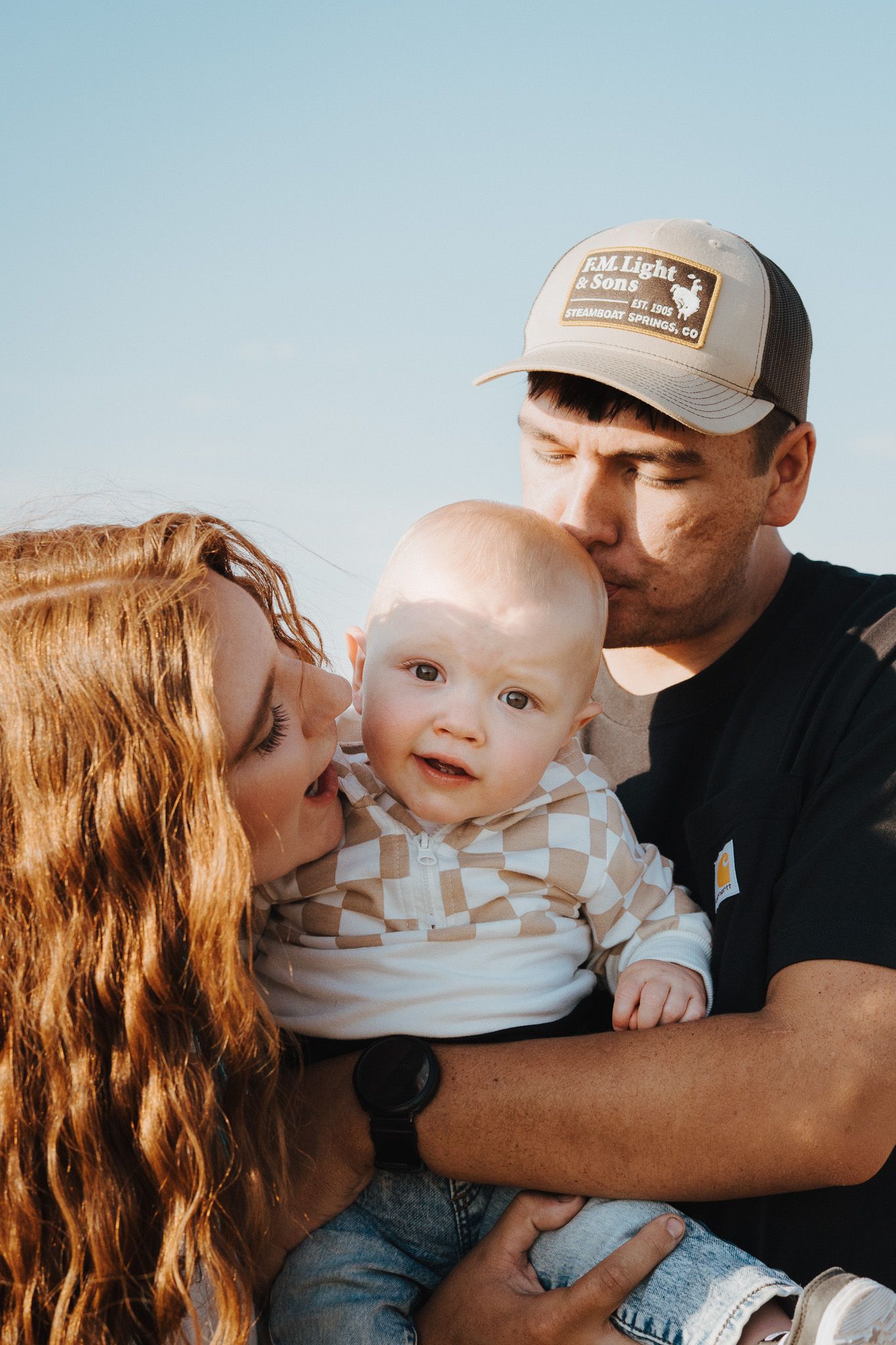 A family shares tender moments together in a outdoor portrait photograph.