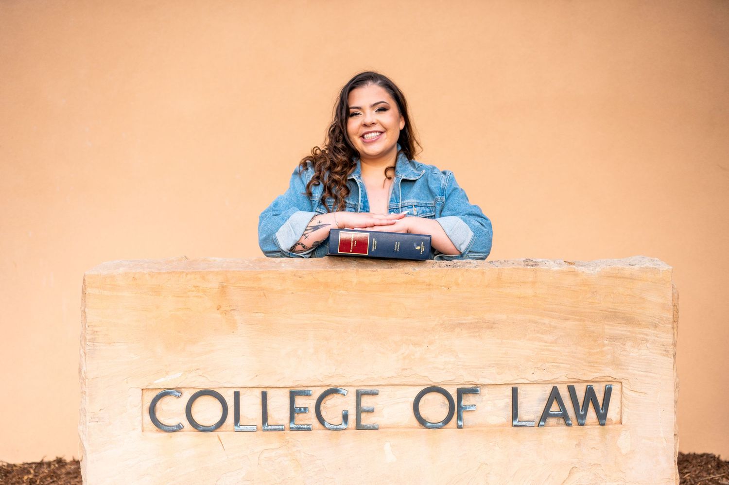 A woman standing behind a stone sign that reads 