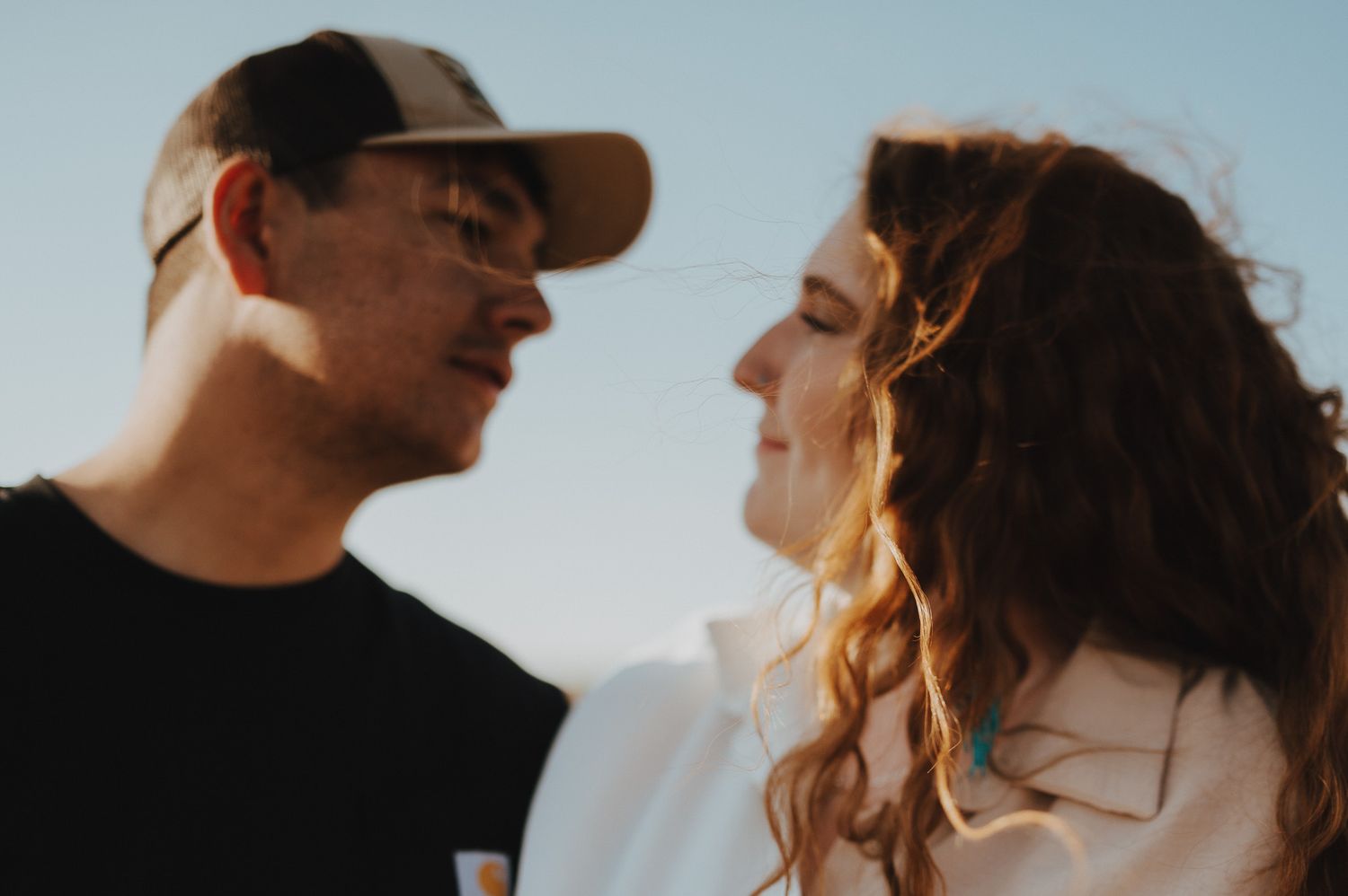 A romantic couple shares tender moments in golden sunlight during an outdoor photo session.