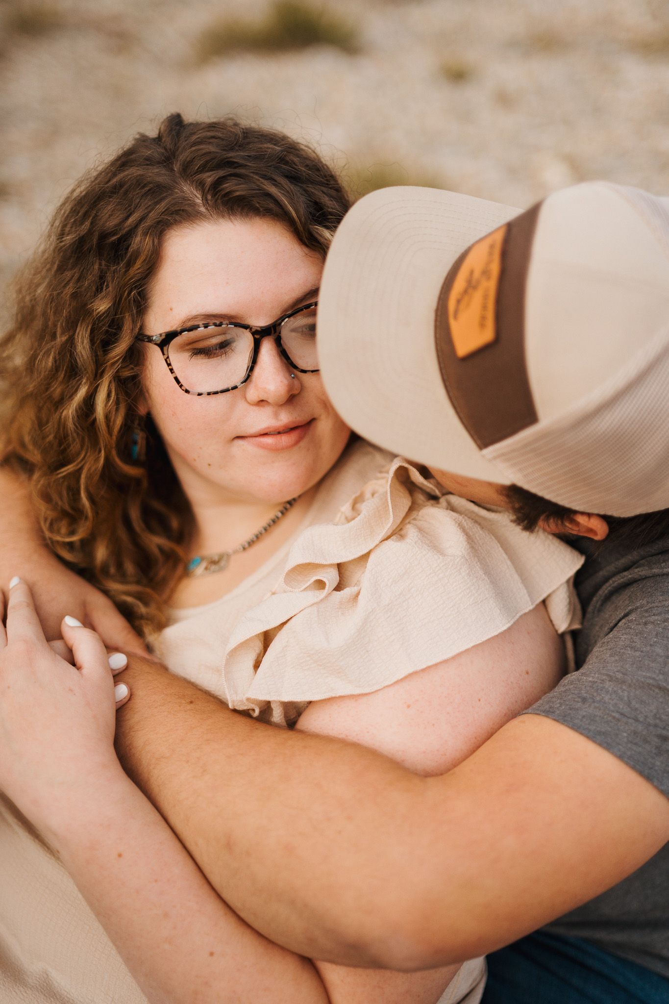 A romantic couple embraces tenderly in soft natural lighting while wearing casual attire.