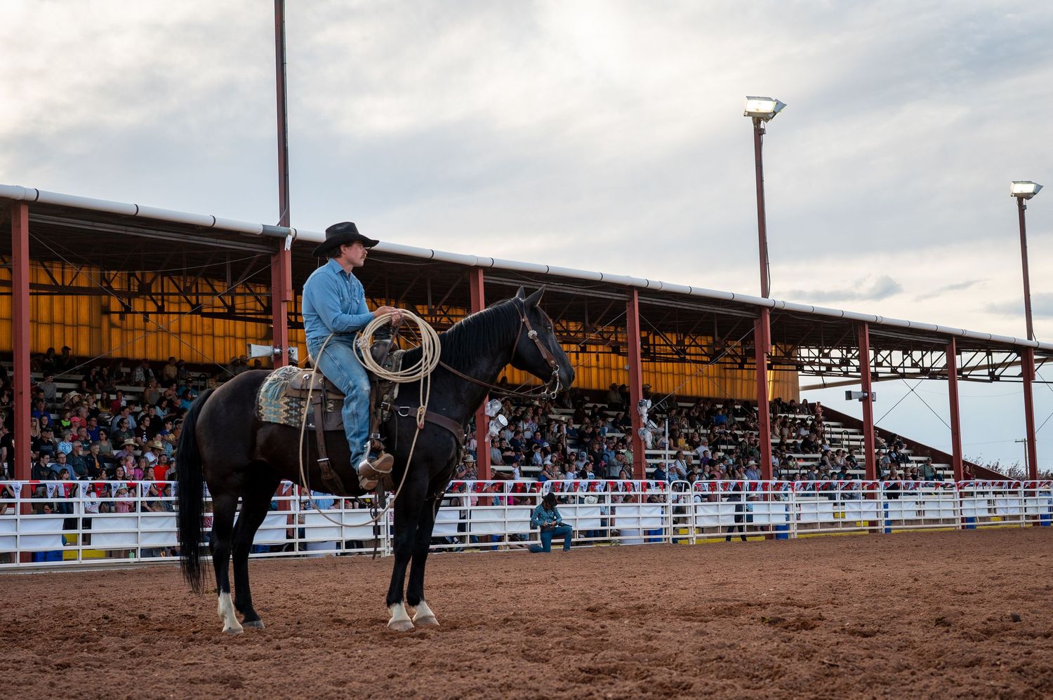 A cowboy on a dark horse in an arena at a rodeo in Wyoming.