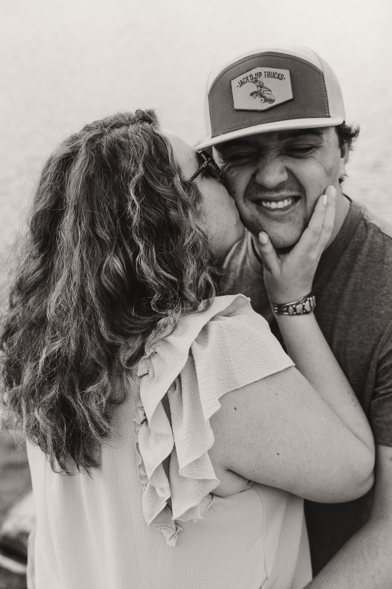 A woman grabbing a man's chin and kissing his cheek.