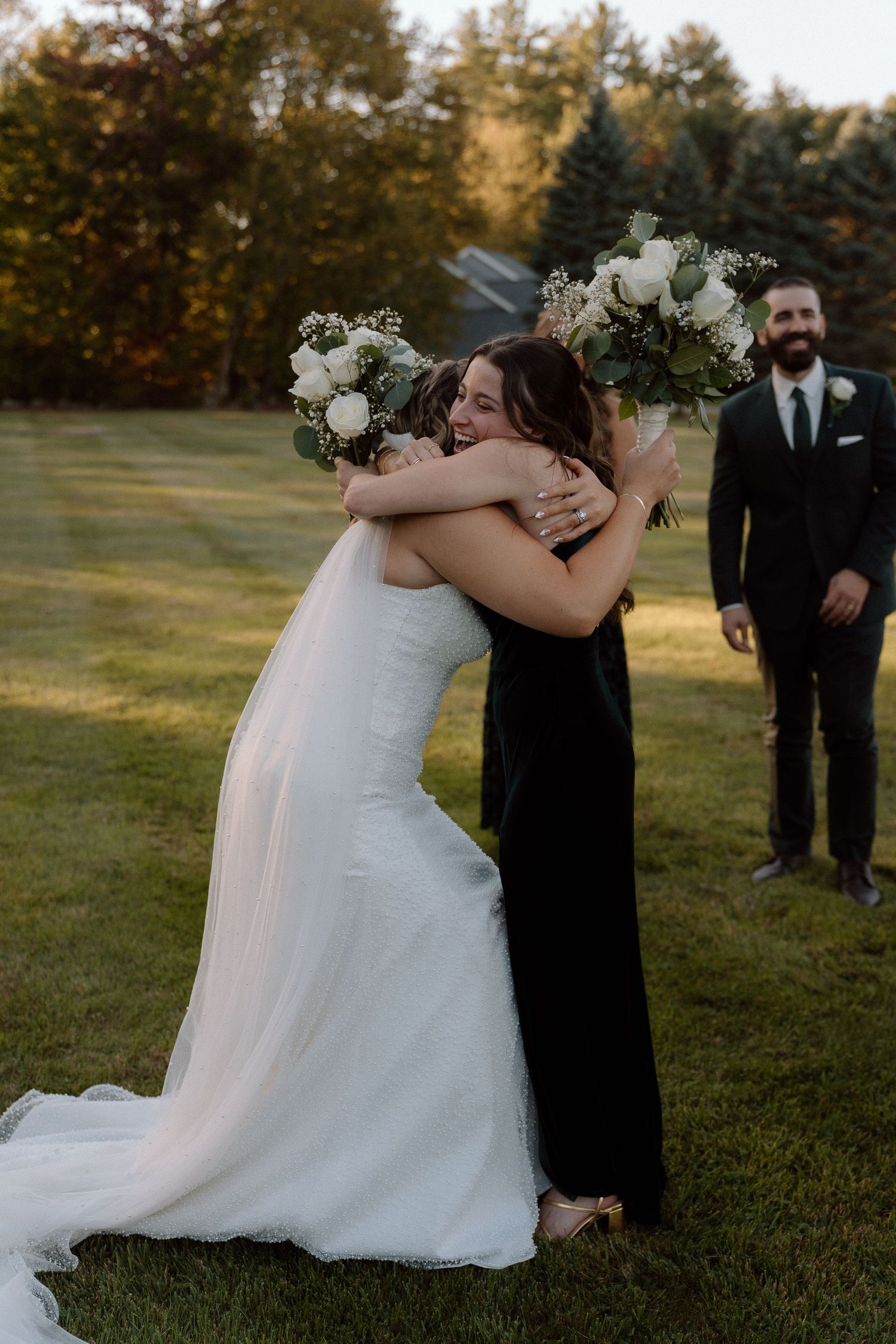 Emotional wedding moment captured outdoors with white floral bouquet and flowing dress details.
