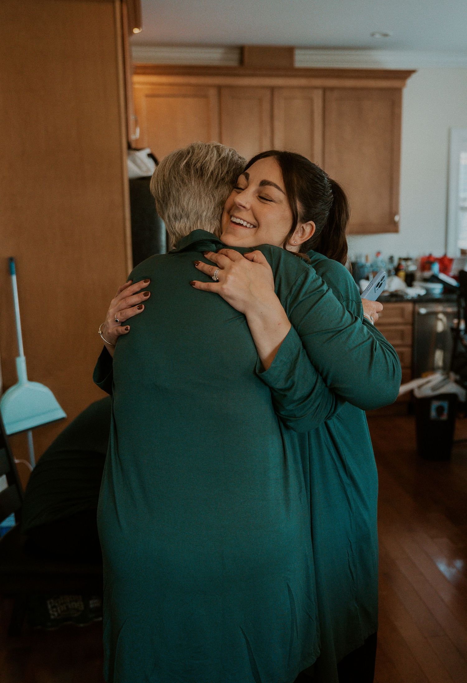 Four sequential photos show two people sharing an emotional embrace in a warmly lit room with wooden cabinets.