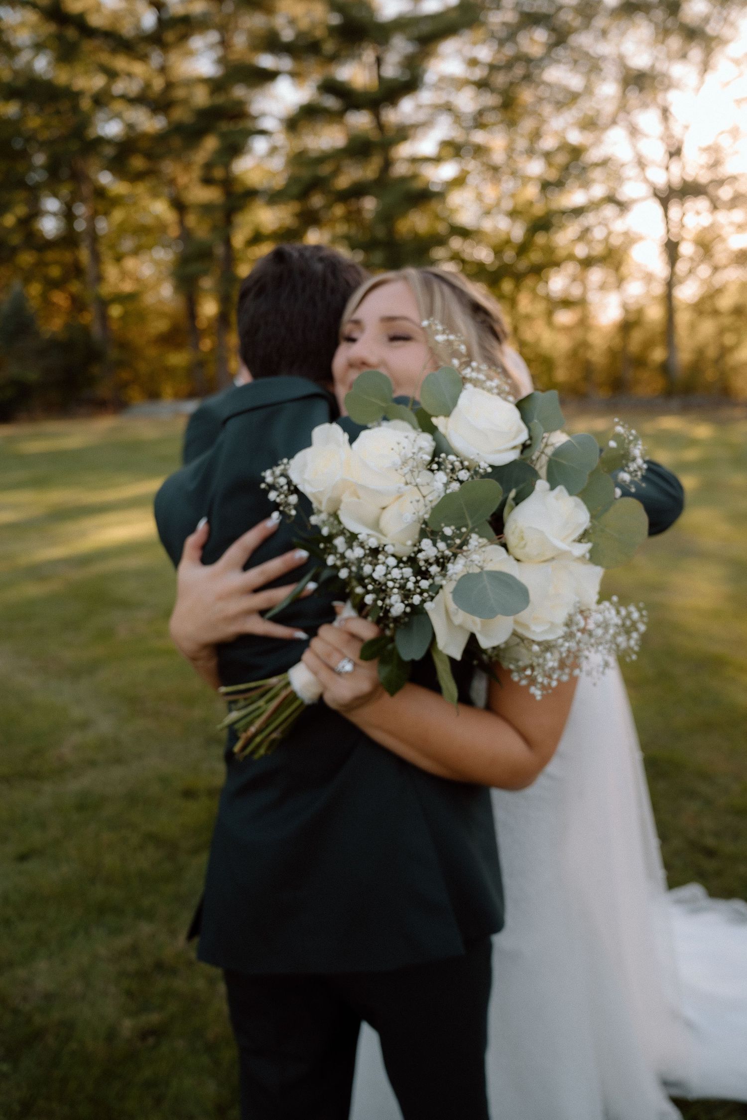 White roses and baby's breath bouquet featured in an emotional outdoor wedding moment.