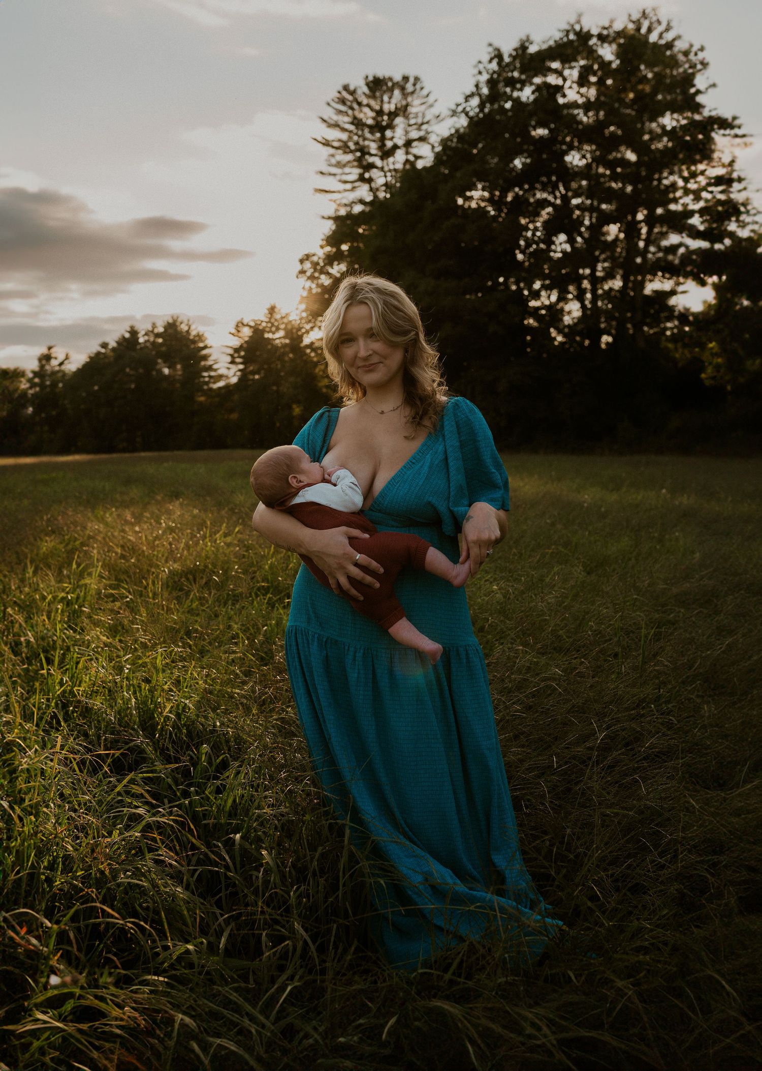 Someone in a teal dress sits in a meadow during golden hour.