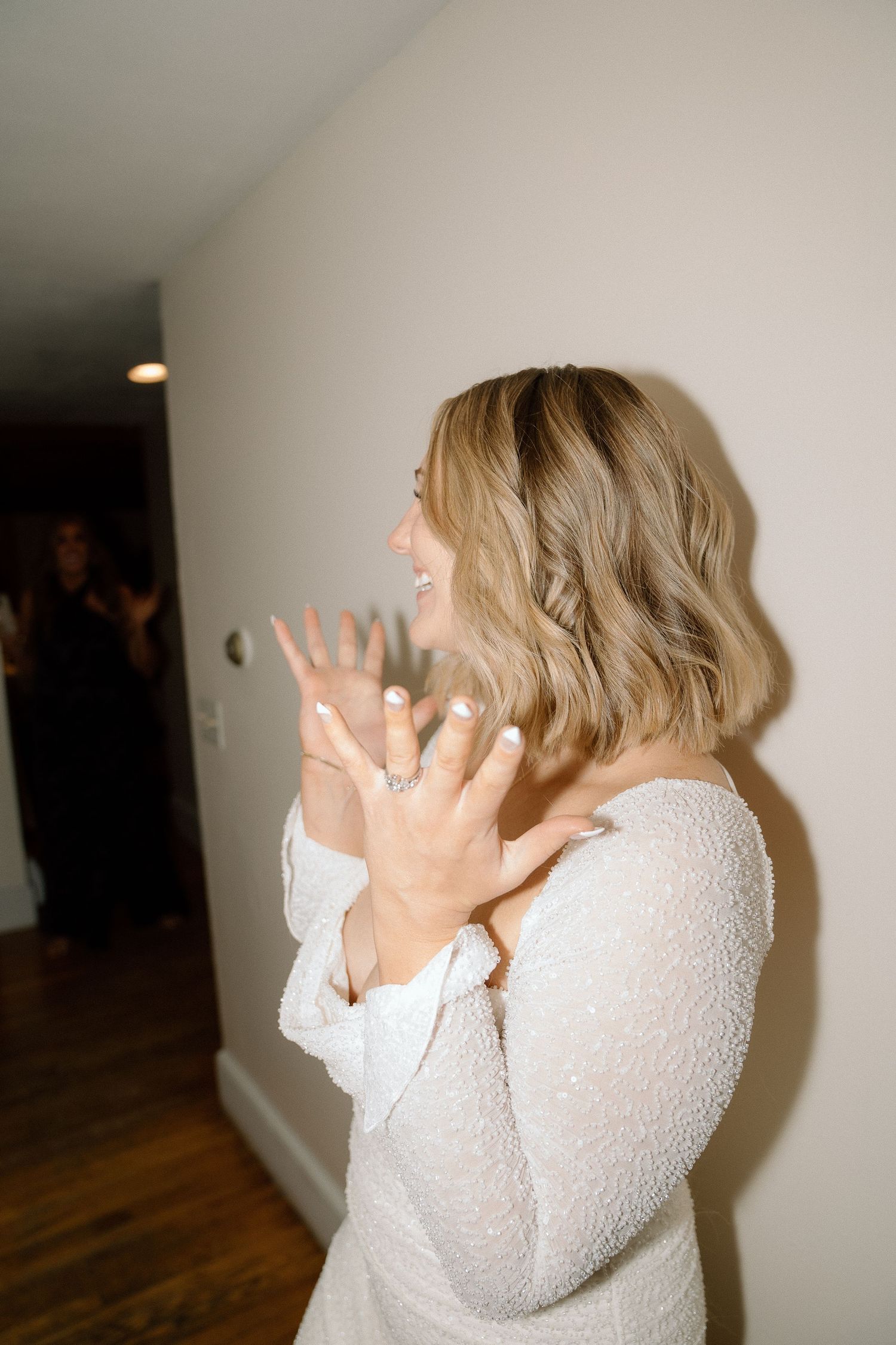 A person in white dress shows excitement while looking to the side.