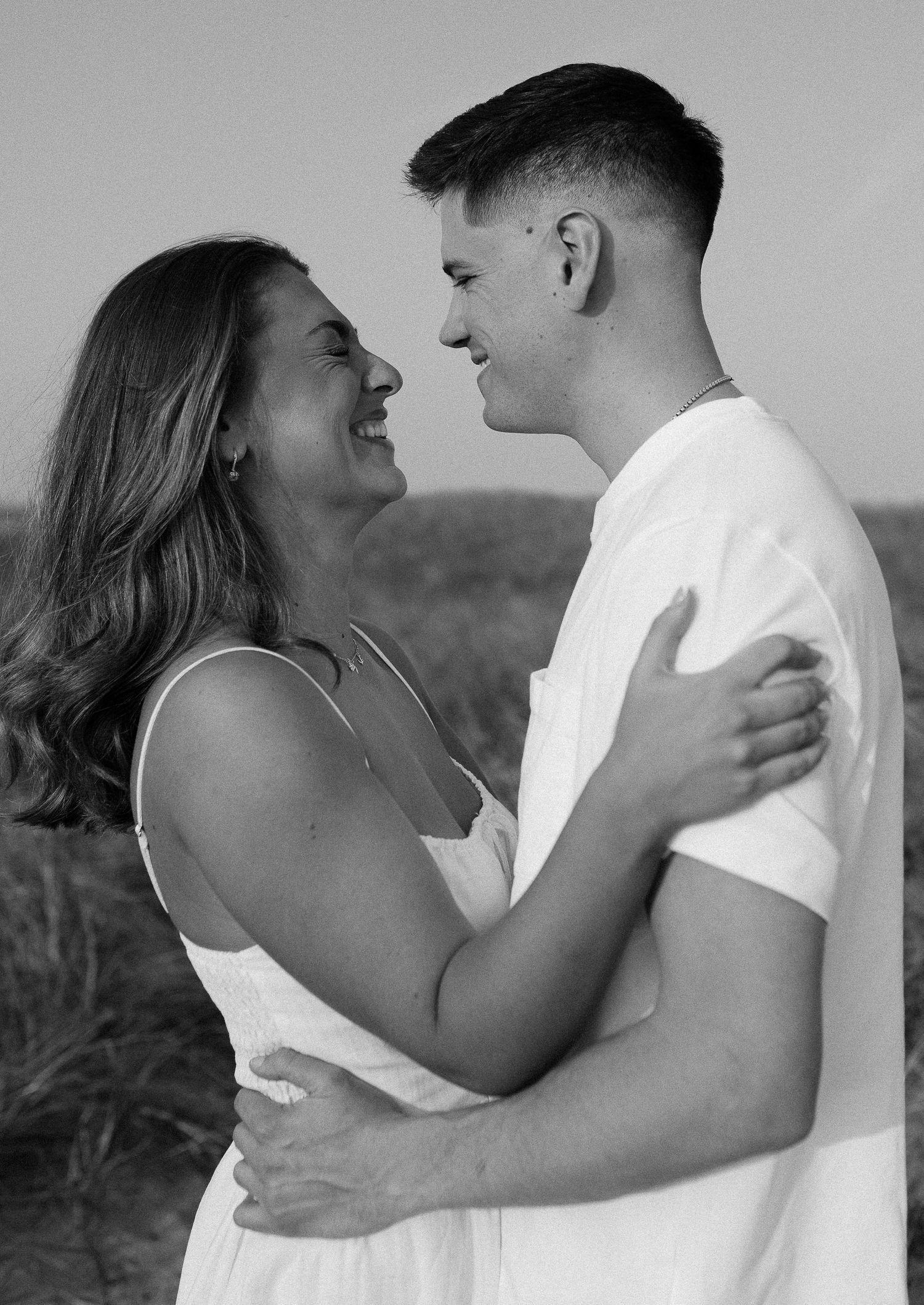 Black and white intimate portraits of a couple in white clothing sharing tender moments together.