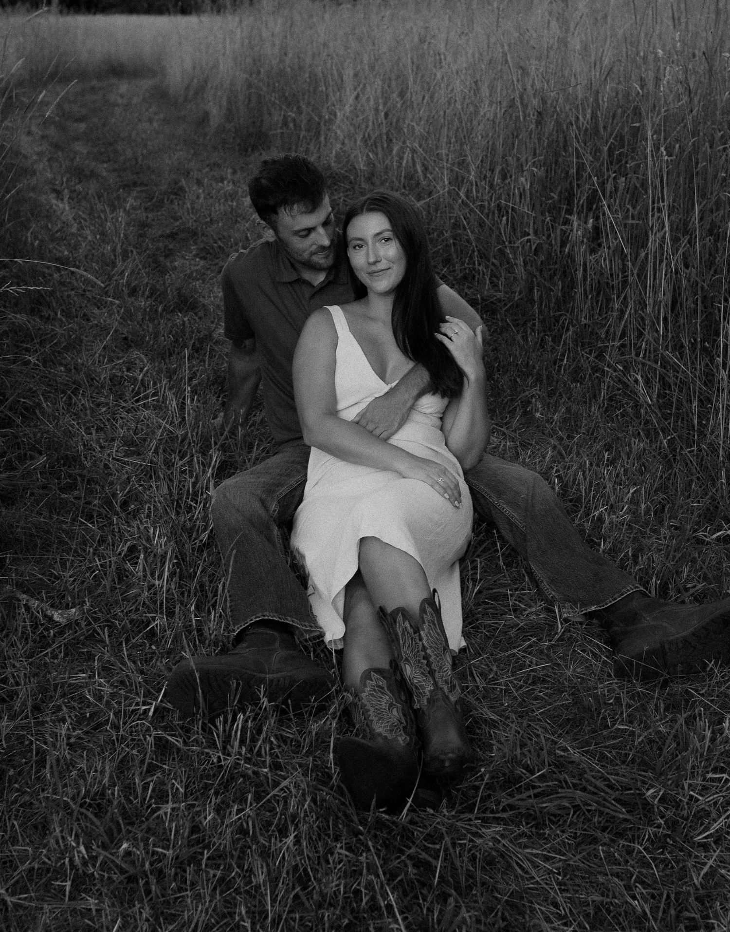 Black and white photos of a couple lounging together in tall grass during a romantic shoot.