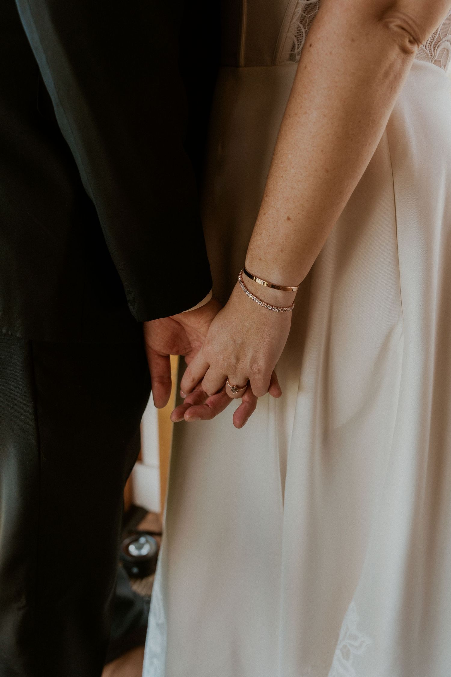 Close-up detail shots of a bride's hands and white wedding dress against a dark background.