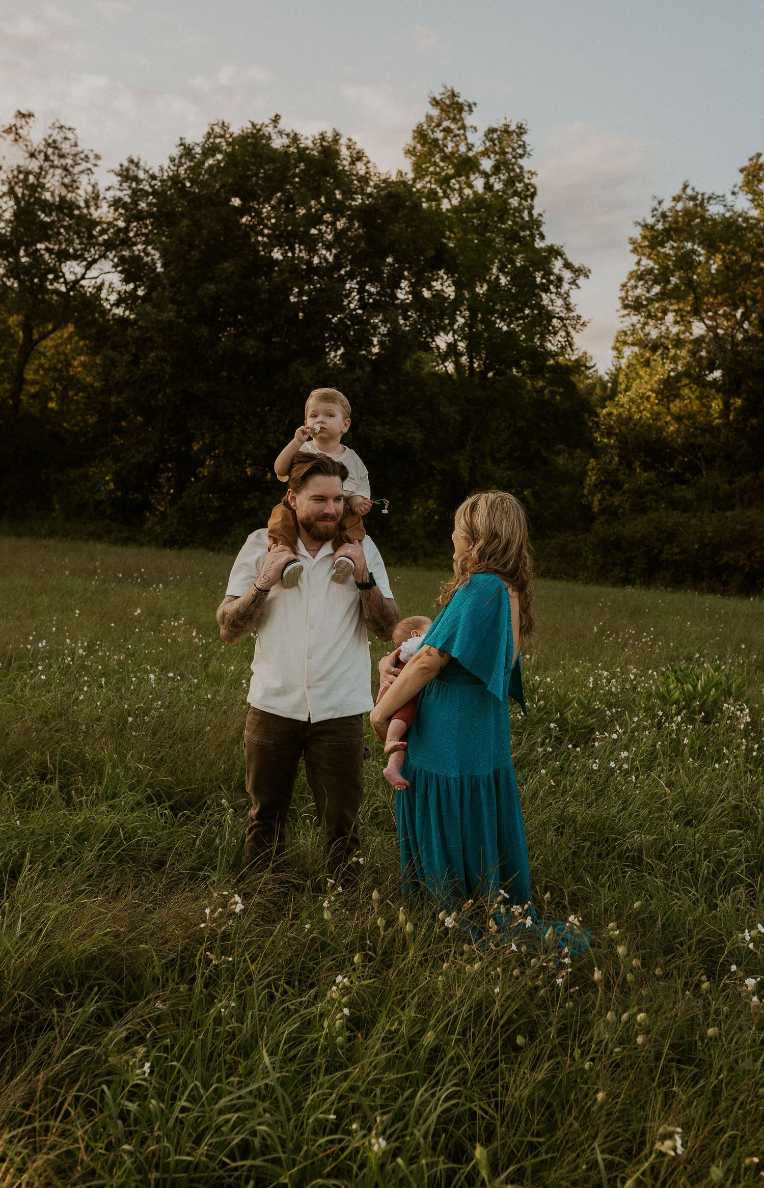 A family enjoys a golden hour moment together in a wildflower meadow at sunset.