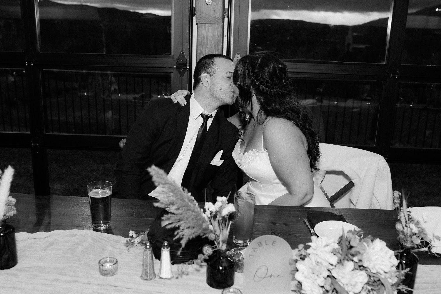 A series of black and white wedding reception photos showing guests seated at tables with floral centerpieces.