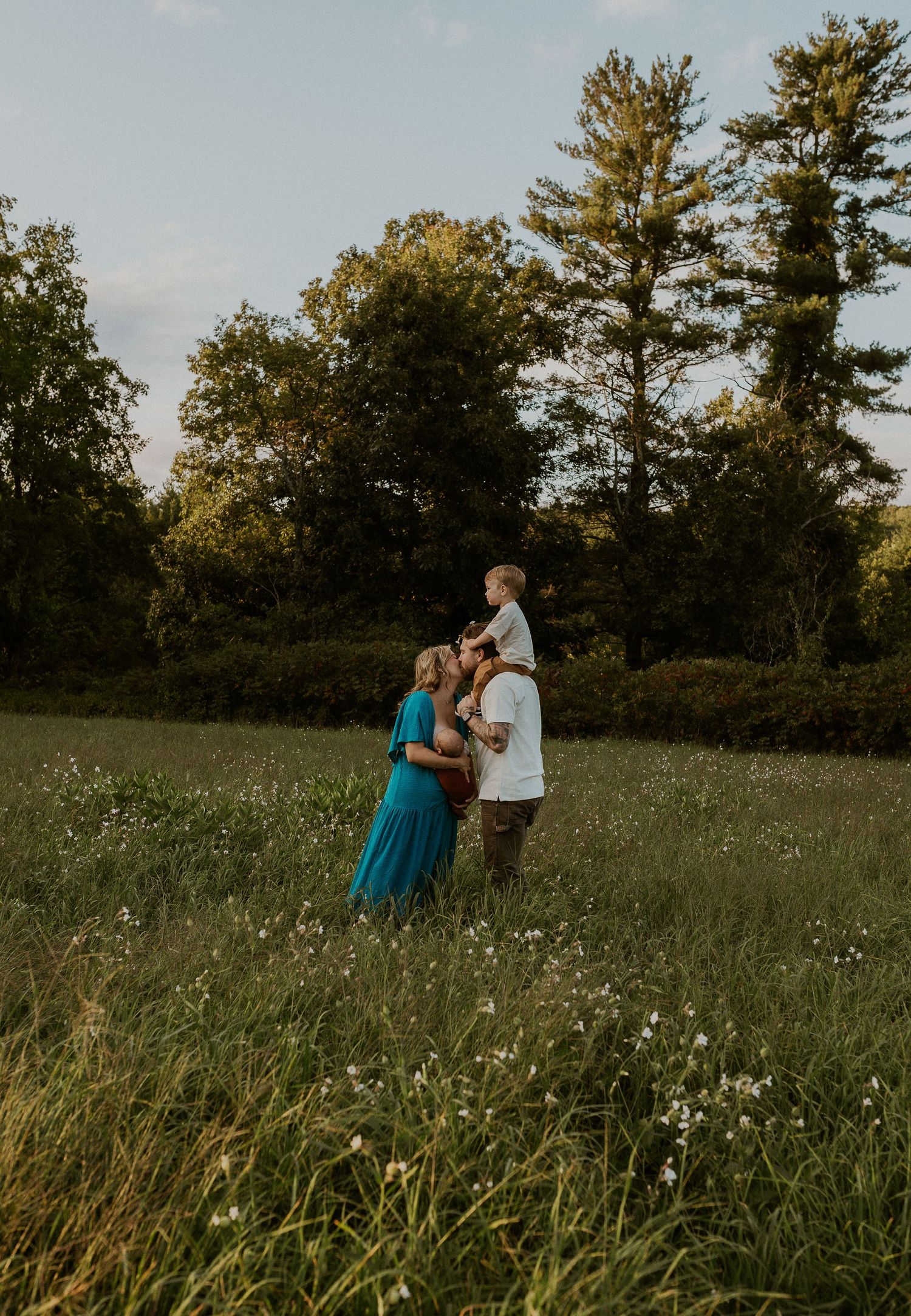 A tender family moment captured in a sunlit field with wildflowers.
