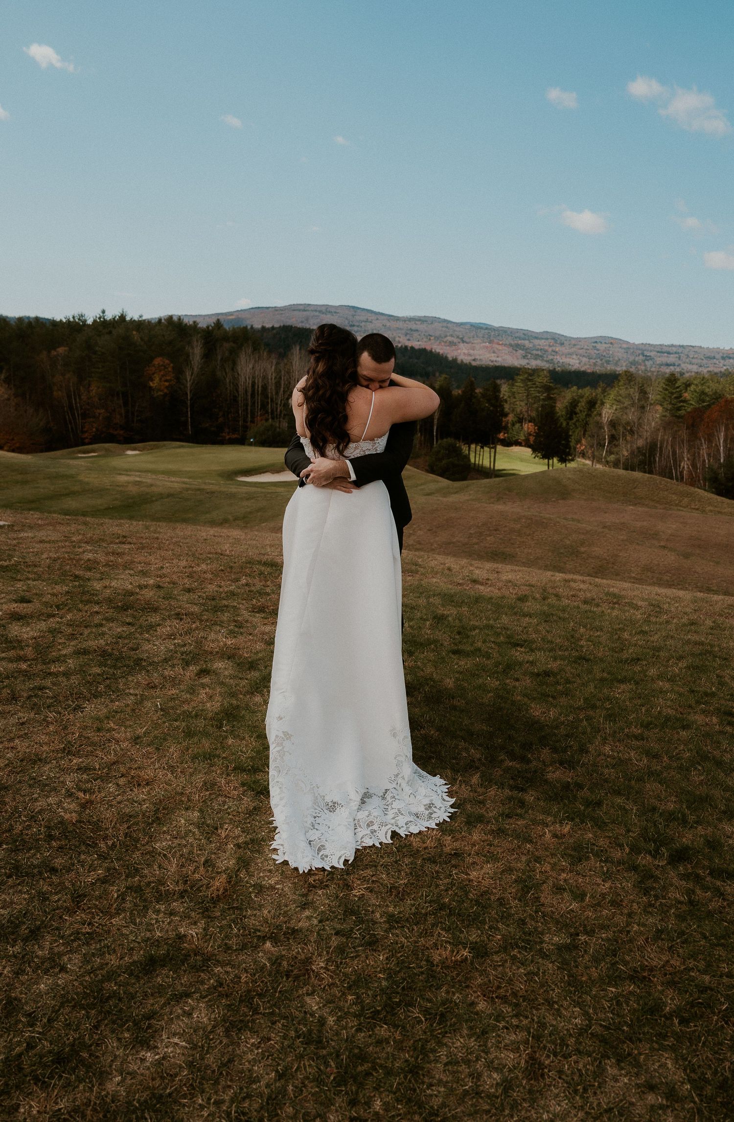 A couple shares a romantic moment in a scenic mountain meadow on their wedding day.