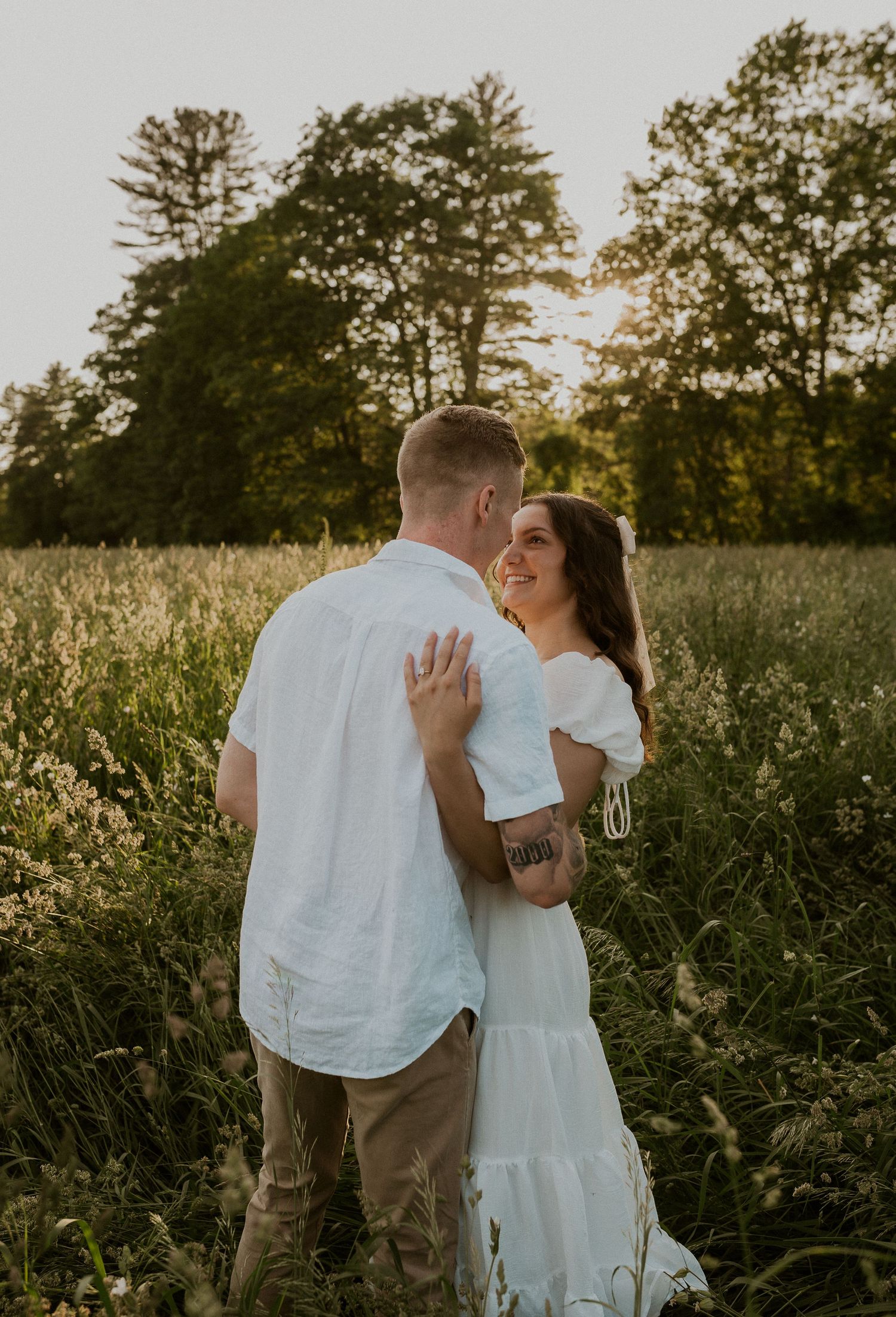 Couple sharing romantic moment in field of tall grass during sunset.