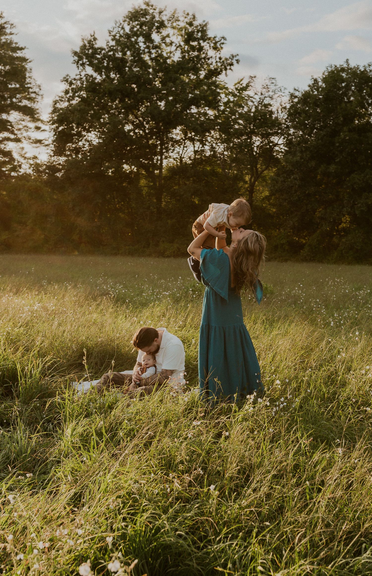 People spending time together in a sunlit meadow with wildflowers and tall grass.