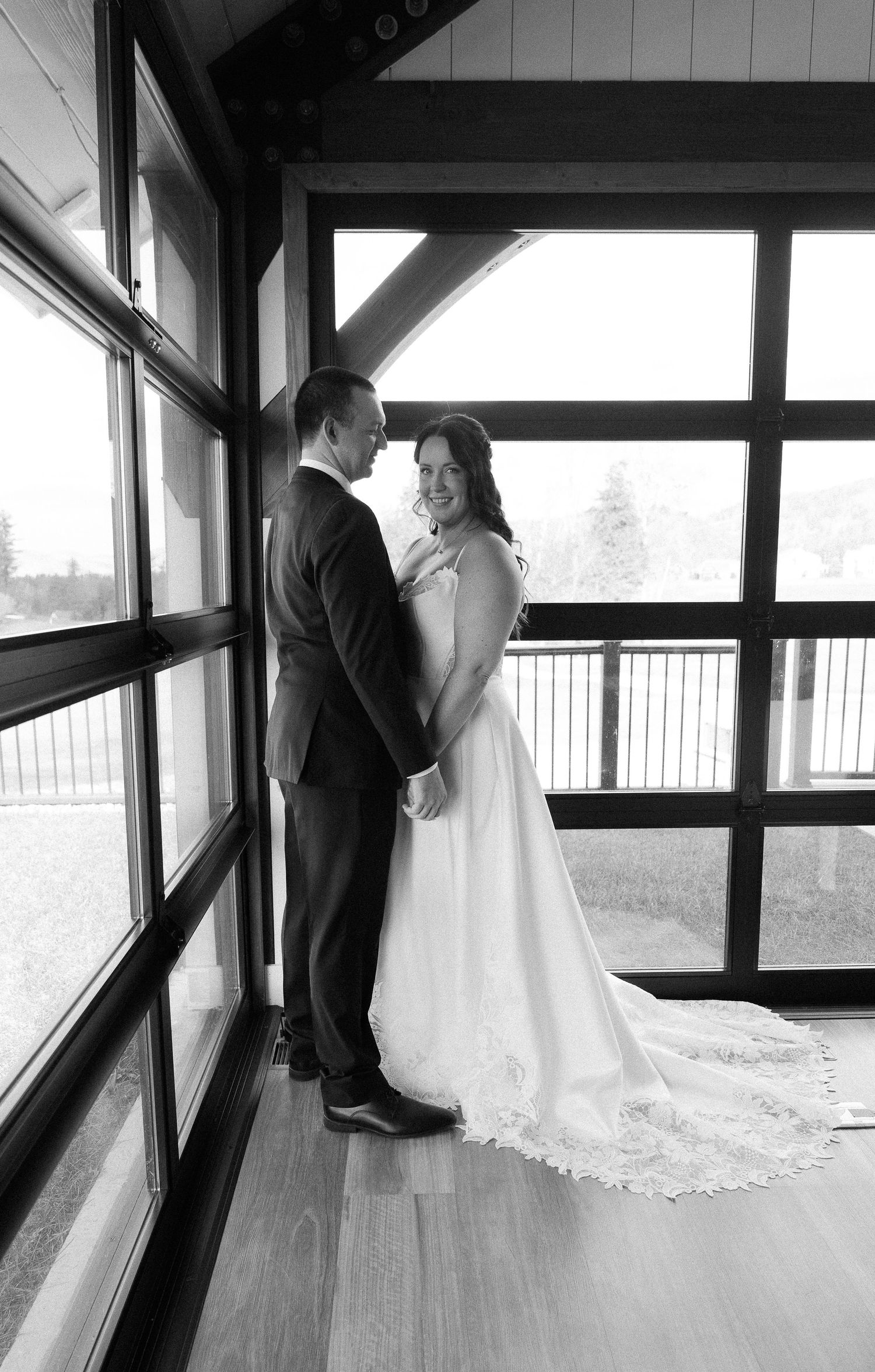 A romantic wedding sequence showing a couple in formal attire by large windows in black and white photography.