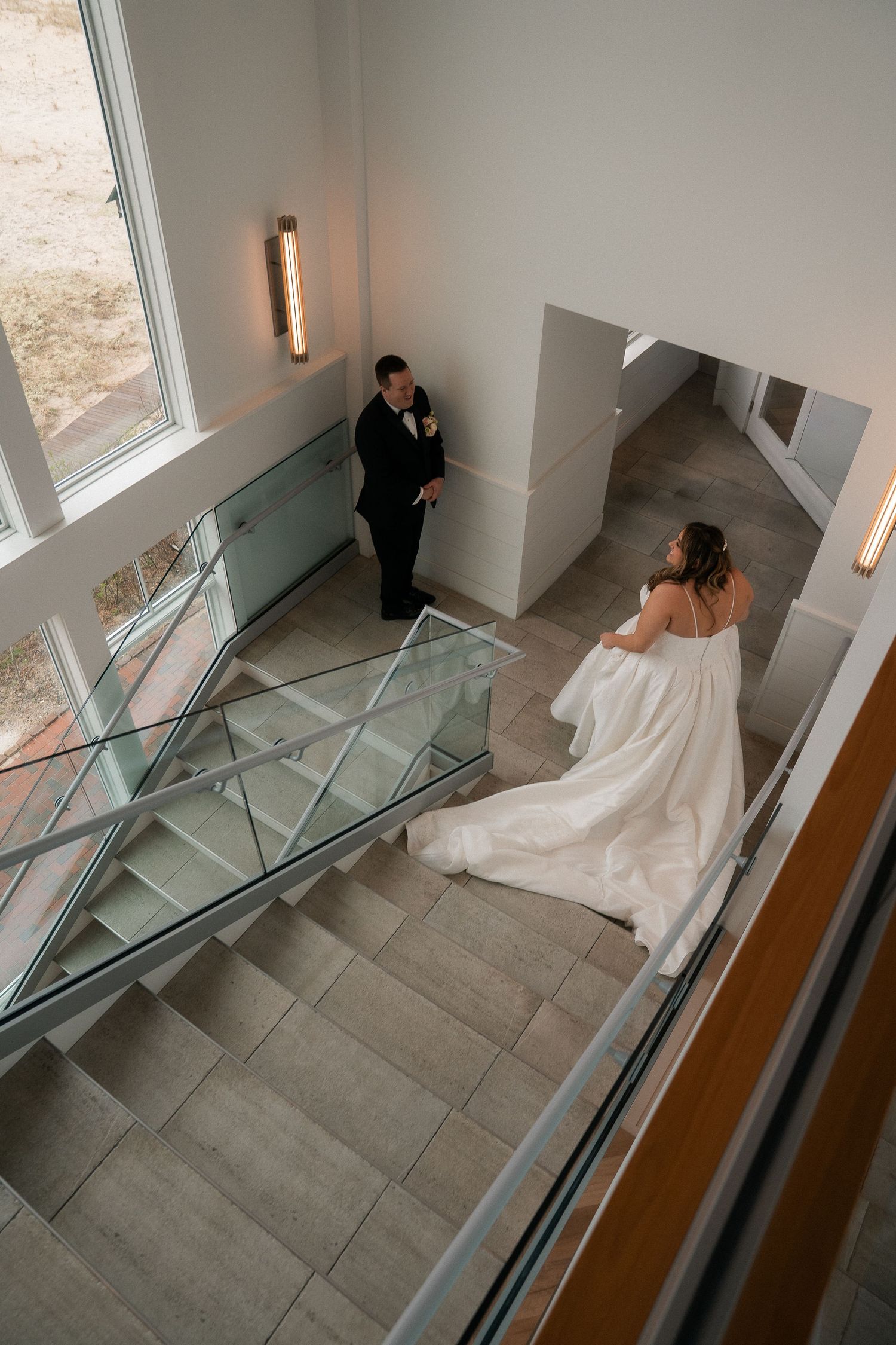 Aerial view of bride and groom sharing first look moment on elegant modern staircase.