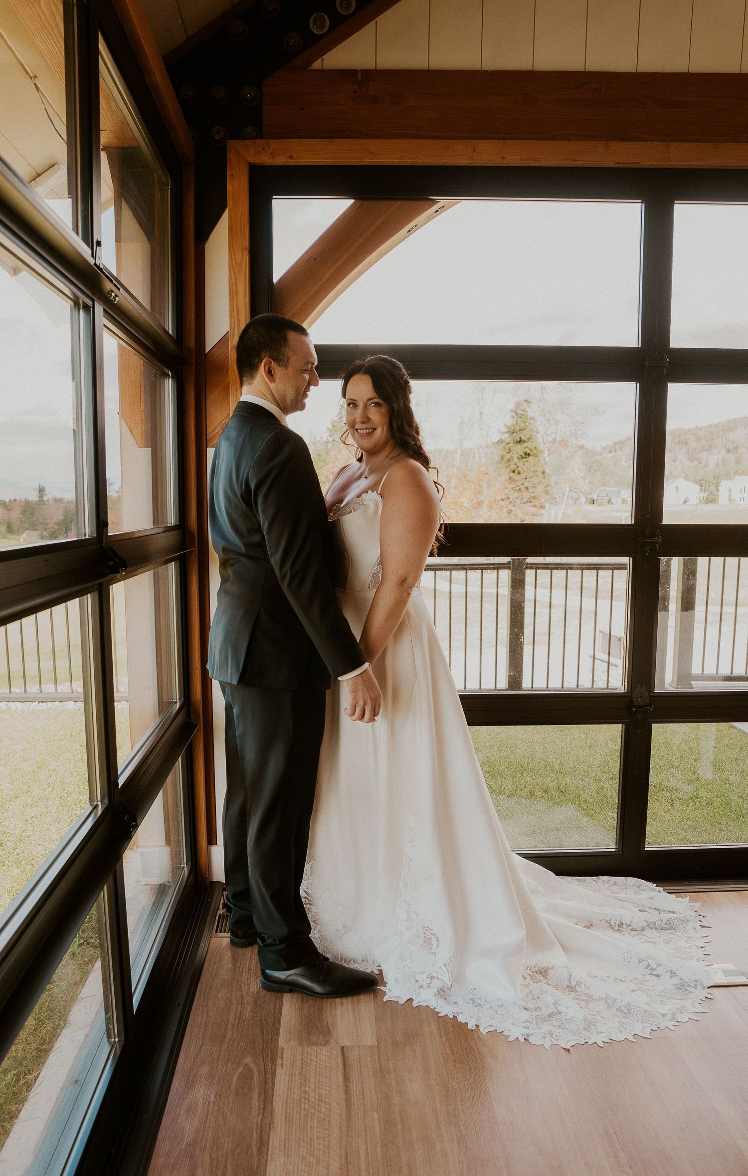 Wedding couple sharing intimate moments in a modern indoor venue with large windows.