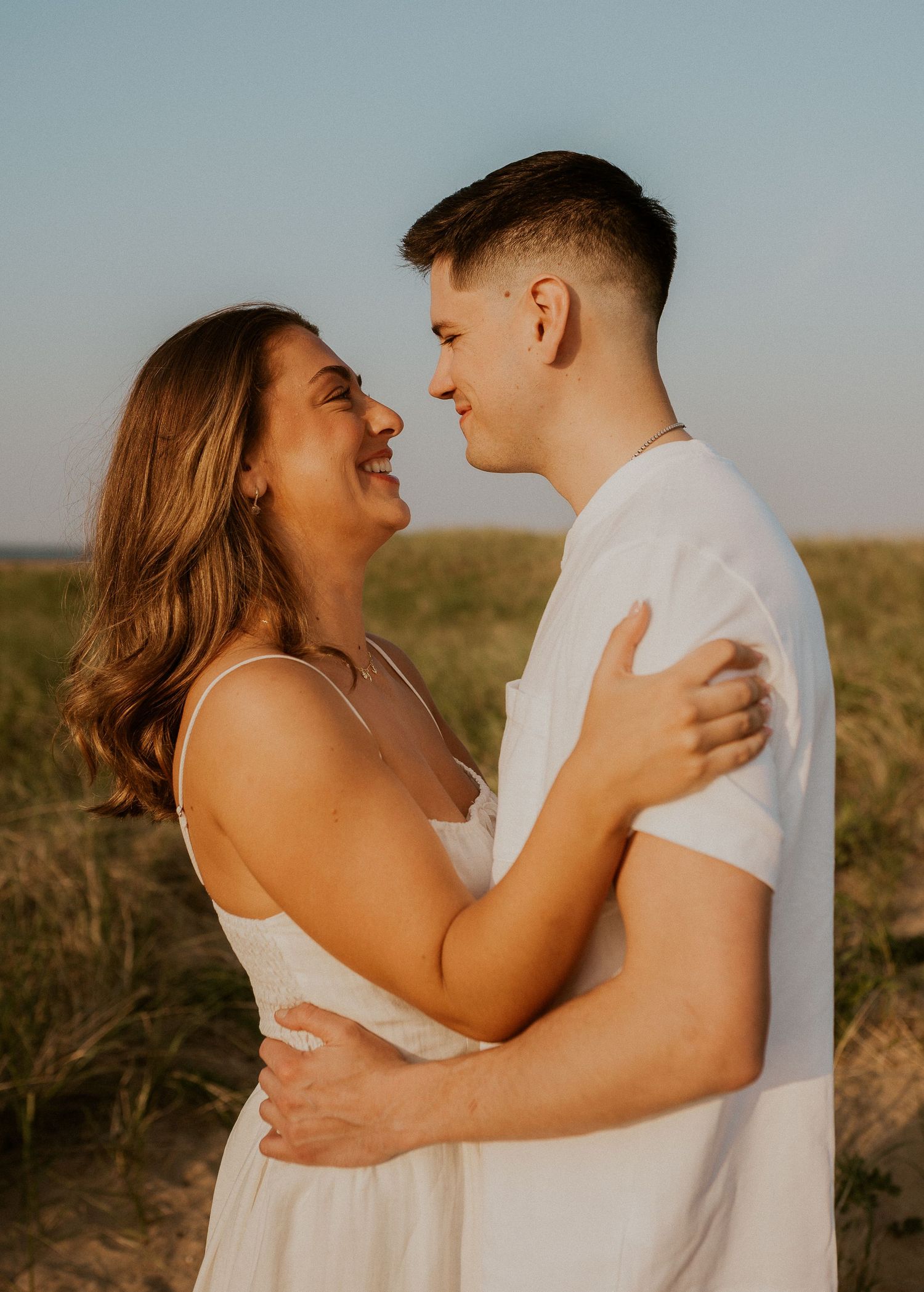 Close-up photo series of a couple in white clothing sharing joyful laughter and embraces outdoors.