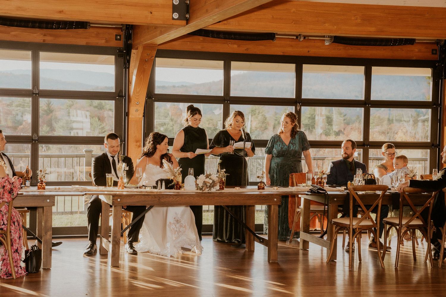 Reception venue with rustic wooden beams and large windows showcasing natural light and mountain scenery.
