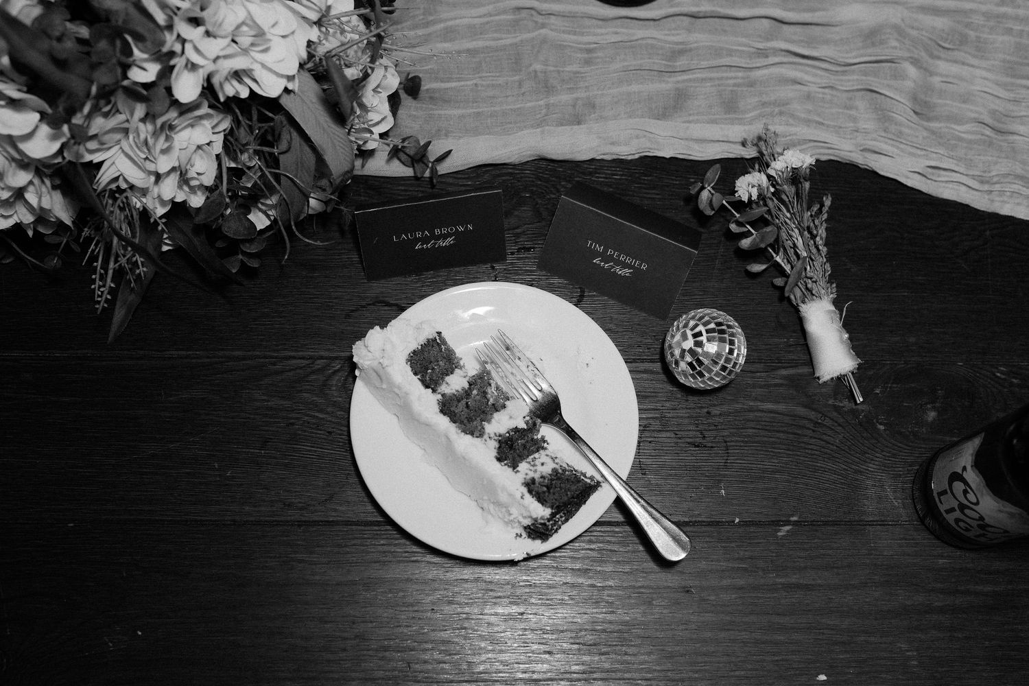 Black and white overhead shot of a slice of wedding cake on a plate with flowers.