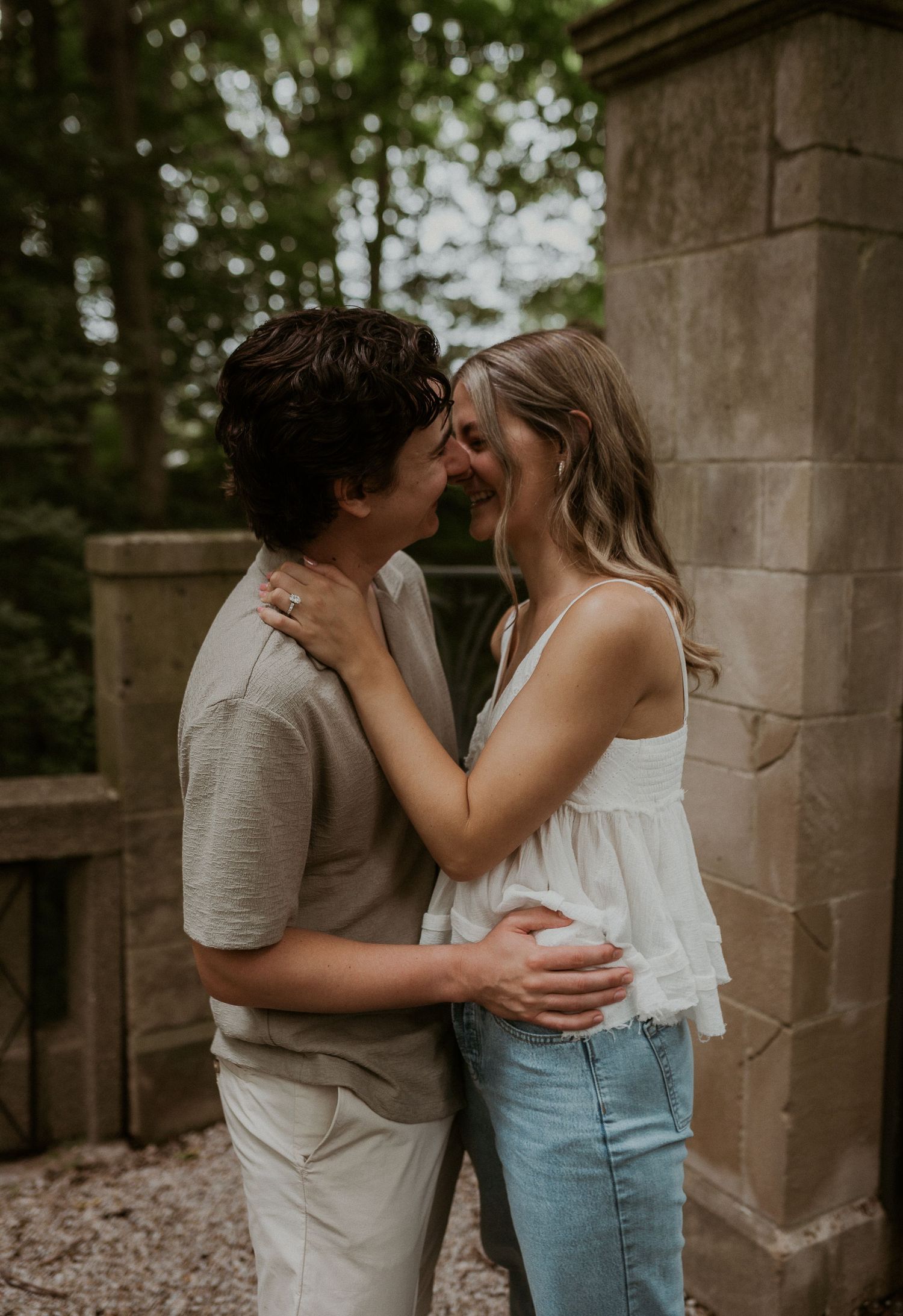 Romantic couple sharing intimate moments against stone wall background.