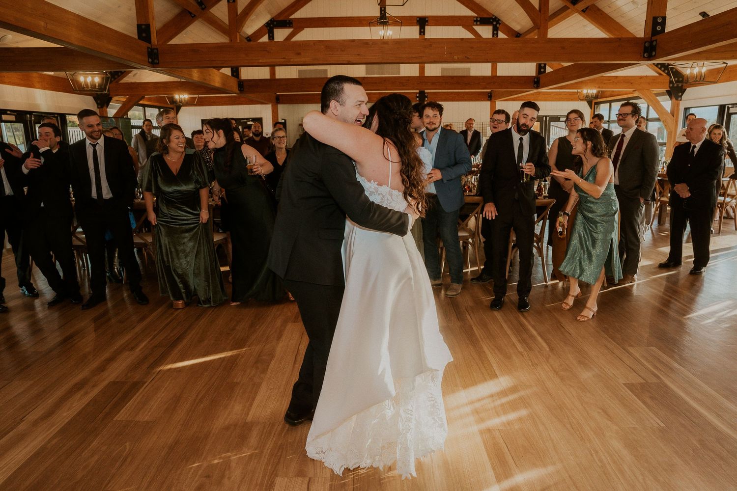 Wedding reception in a rustic wooden venue with exposed beams and large windows overlooking scenic landscape.