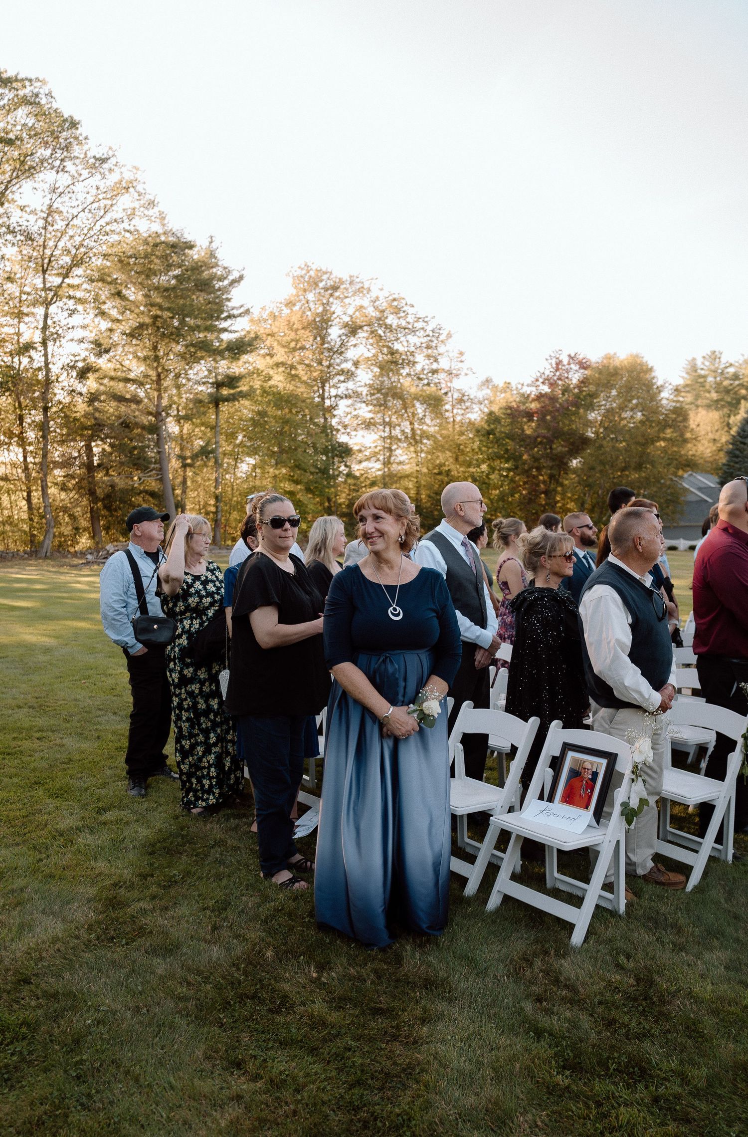 Wedding guests embrace and celebrate during an outdoor ceremony with white chairs.