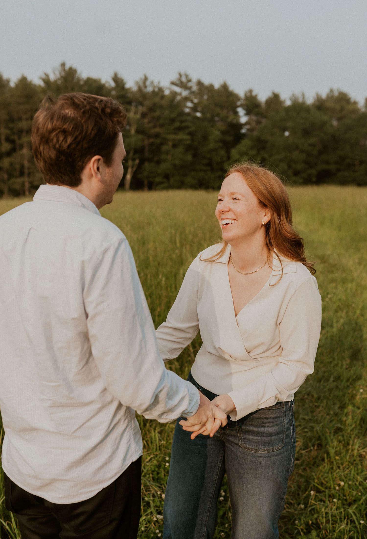 A couple shares a joyful moment together in a sunny meadow.