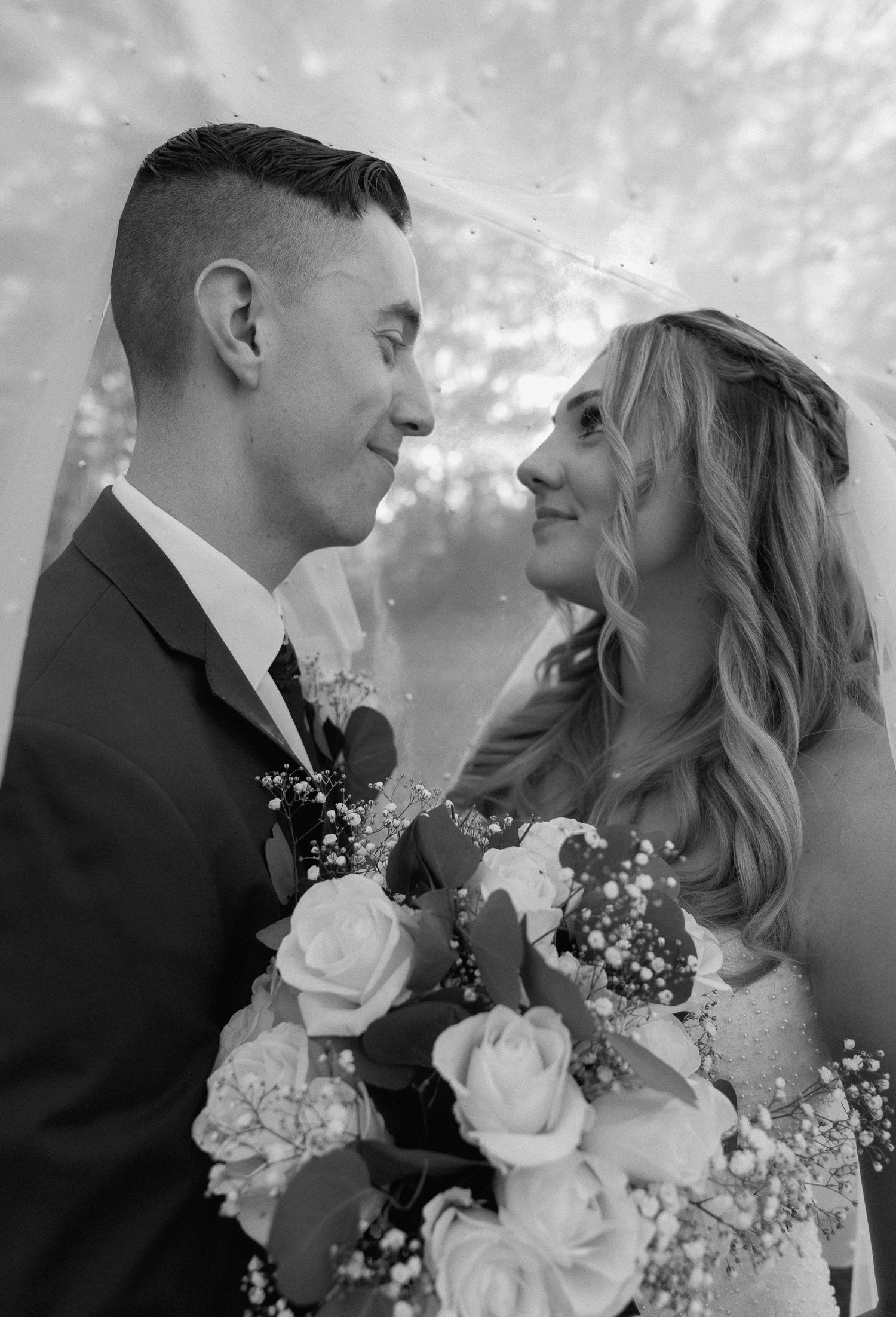 Black and white wedding portrait series featuring romantic moments with white roses and baby's breath bouquet.