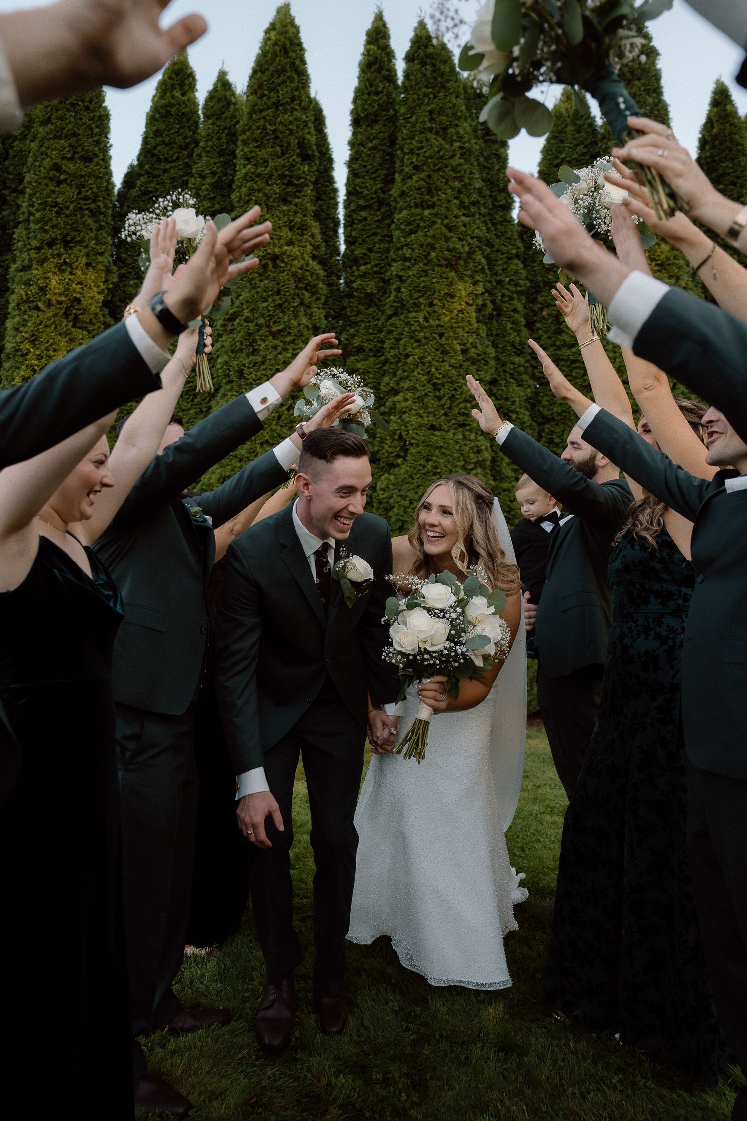 Joyful celebration with wedding party raising hands around the couple.