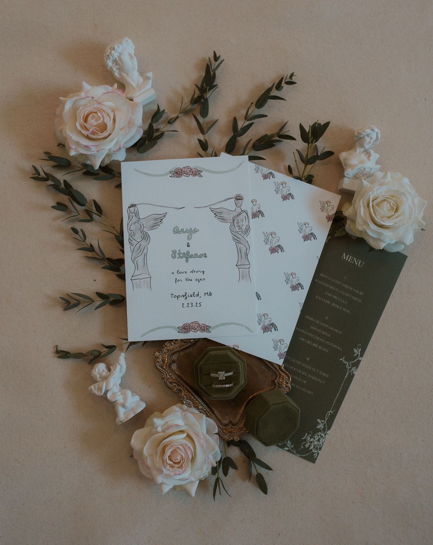 Wedding stationery flat lay featuring white roses and delicate invitation design.