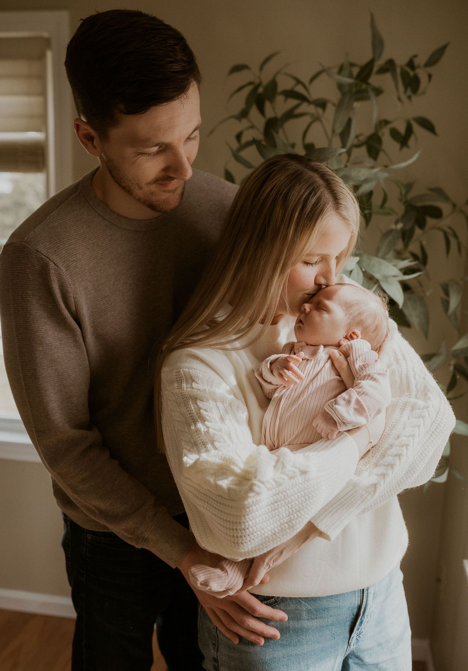 A tender family moment with parents cradling their newborn baby in a cozy home setting.