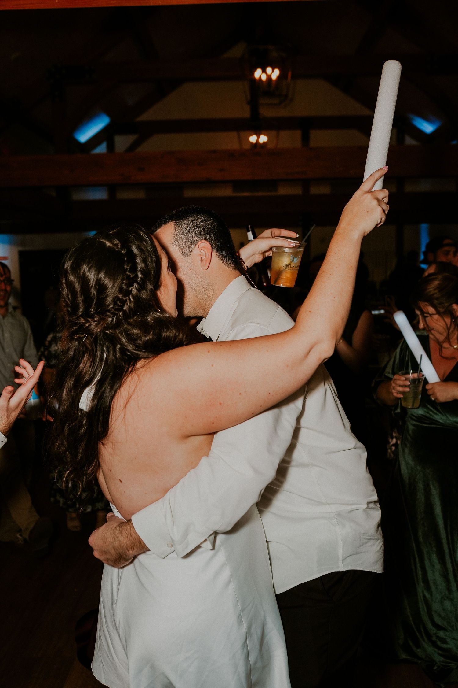 People dancing and celebrating at a dimly lit party venue with raised arms and joyful energy.