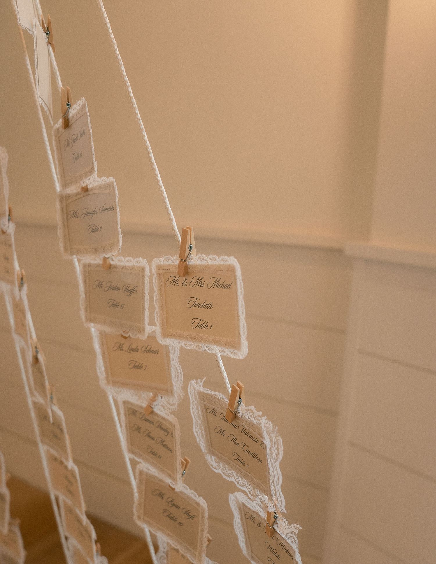 Elegant wedding seating chart cards clipped to string with wooden clothespins at reception venue.