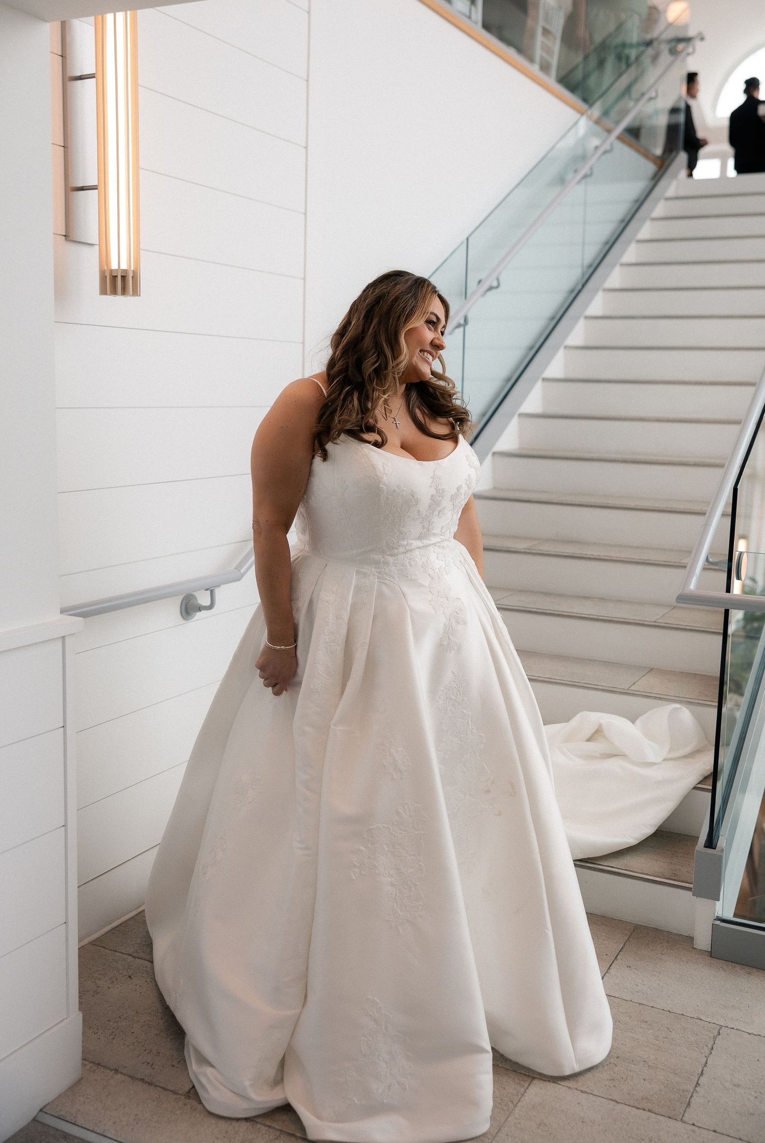 Bride in a strapless ball gown wedding dress with lace bodice poses on modern staircase.