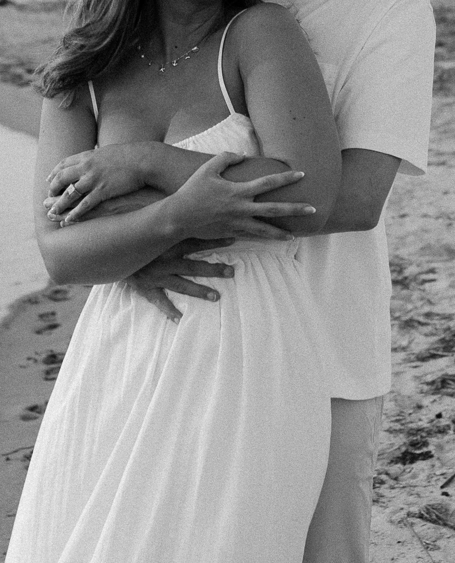 A close-up shot of a couple embracing on the beach in black and white.